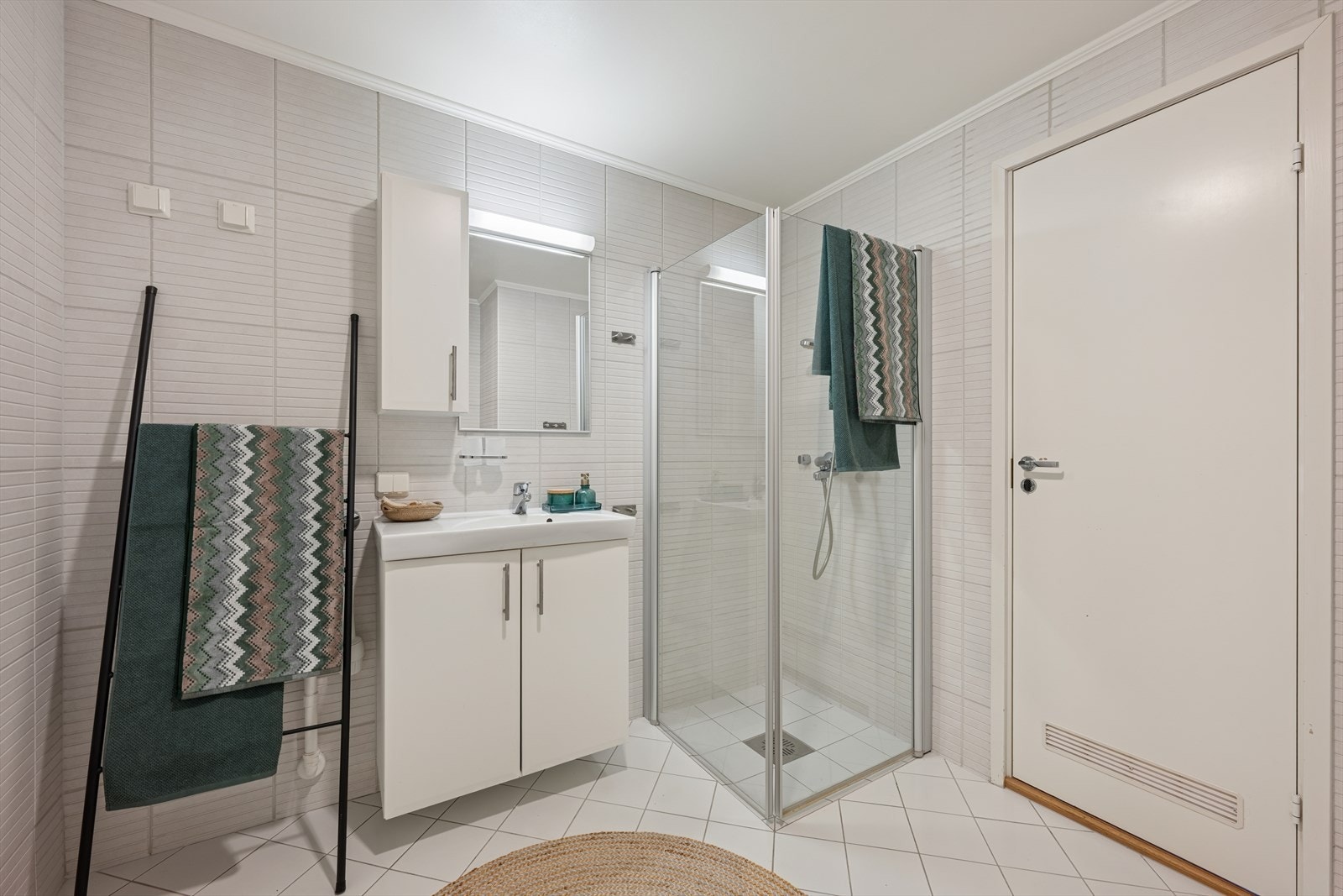 Badet er innredet med nedfelt servant, gulvmontert toalett, dusjvegger og opplegg for vaskemaskin Galleribilde