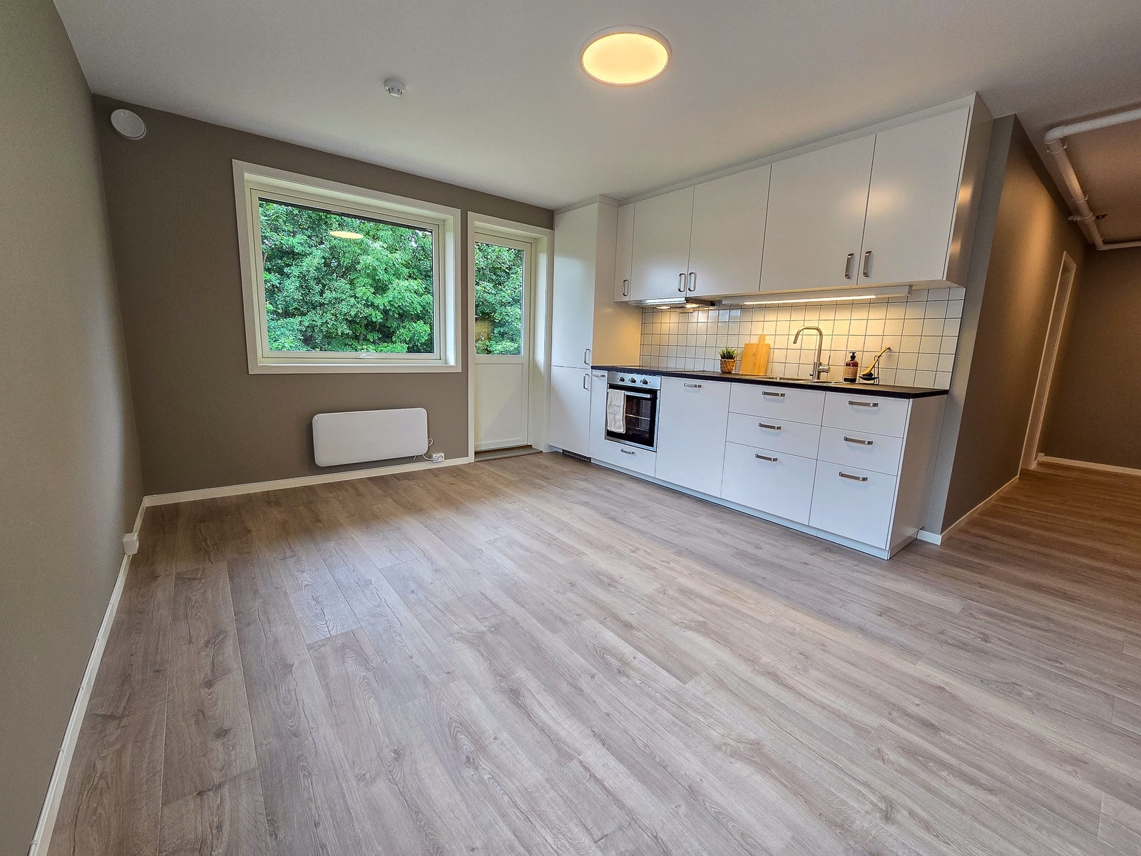 Stue med åpen kjøkkenløsning og utgang til veranda. Leiligheten ble totalrenovert i 2025. Galleribilde