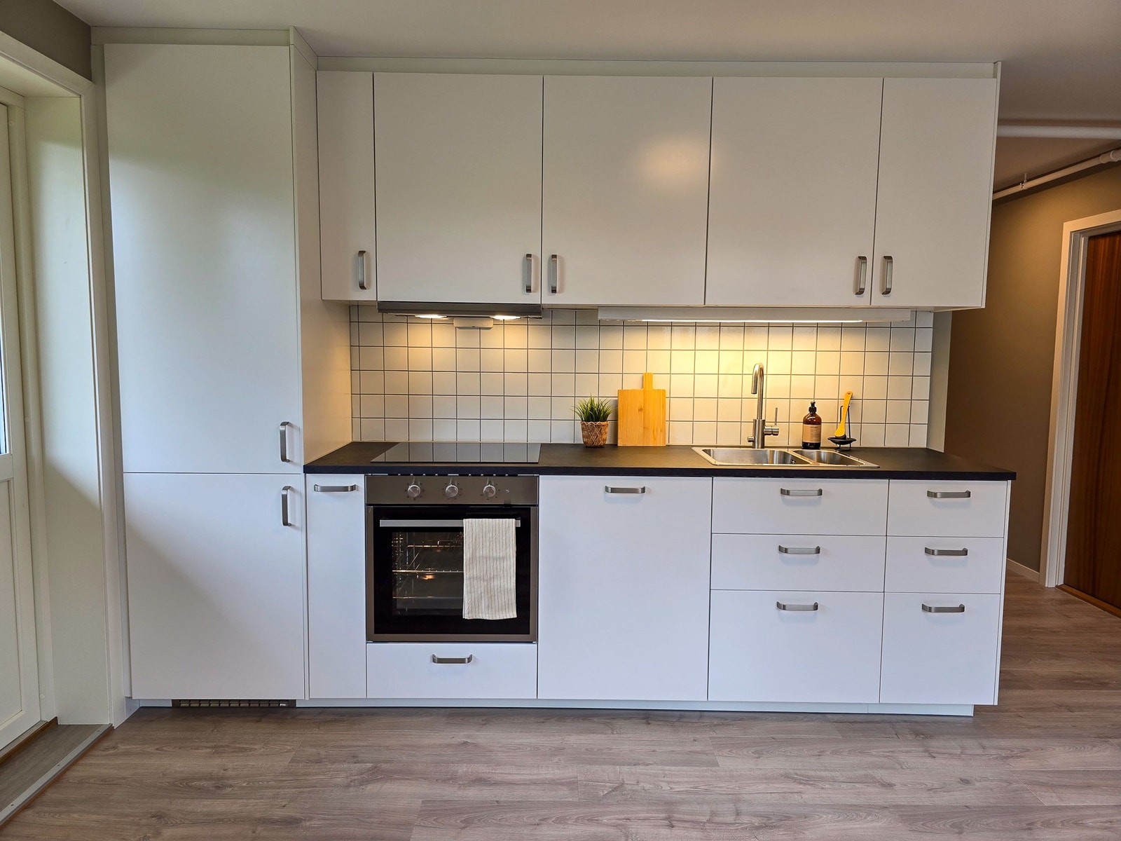 IKEA kjøkkeninnredning med integrerte hvitevarer som kjøl-/fryseskap, oppvaskmaskin, stekeovn og koketopp. Galleribilde