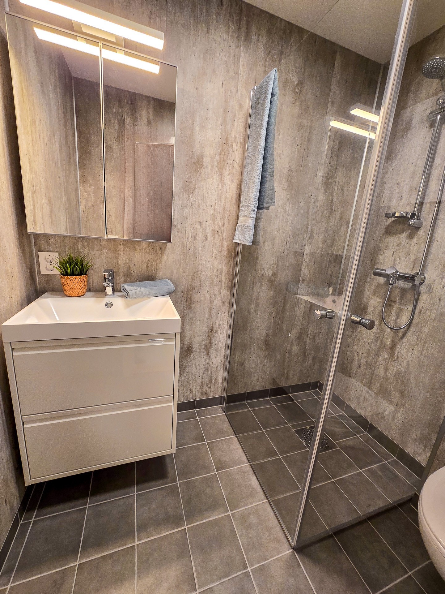 Bad med varmekabler i gulv, servantskap, dusjhjørne og wc. Galleribilde