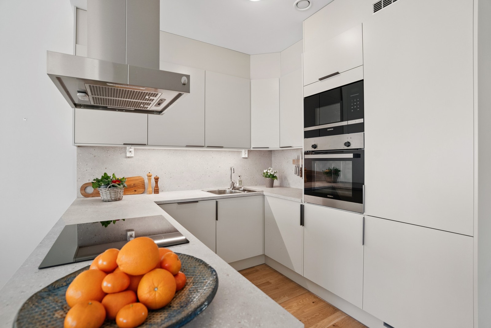 Kjøkkeninnredning fra Sigdal med glatte fronter og laminert benkeplate. Integrerte hvitevarer bestående av stekeovn, koketopp, mikrobølgeovn, oppvaskmaskin og kjøl/frys. Praktisk utforming med god skap- og benkeplass. Galleribilde