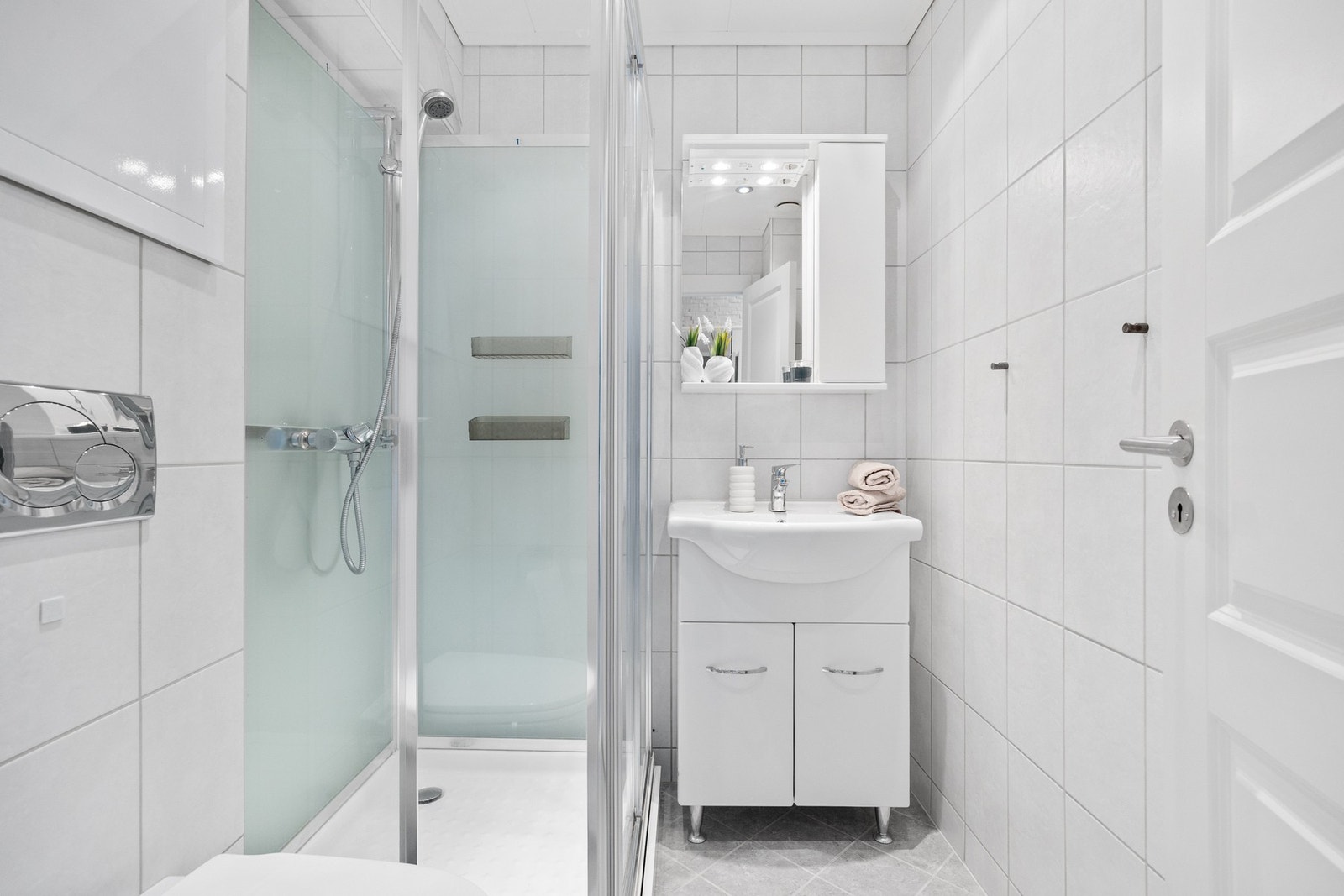 Badet er tidløst innredet med nedfelt servant, dusjkabinett og vegghengt toalett Galleribilde