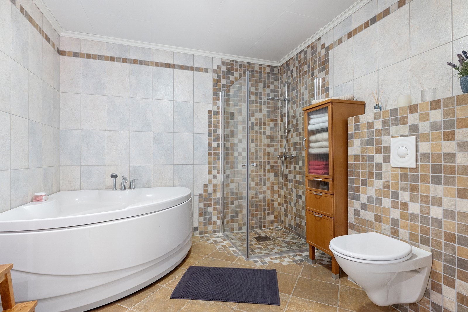 Badet har vegghengt toalett, hjørnebadekar og flott dusjhjørne. Galleribilde