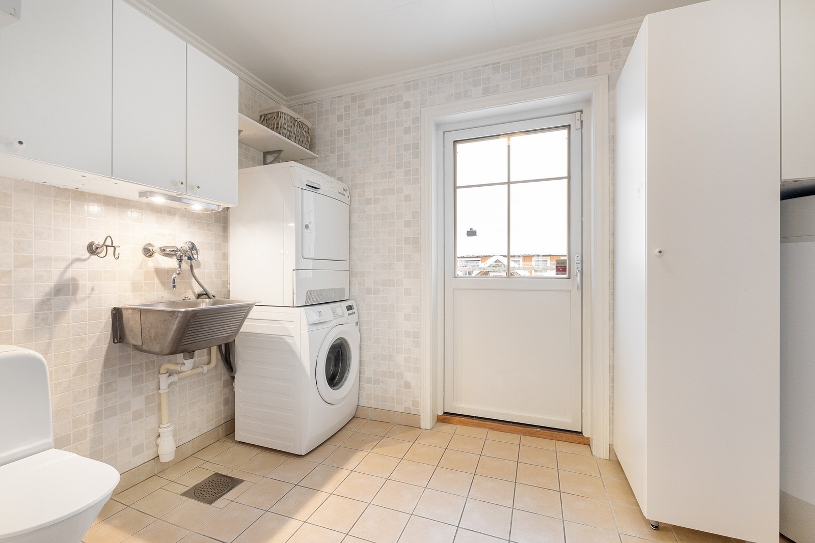 Meget praktisk vaskerom med egen adkomstdør. Innredet med toalett, skyllekum, skap og opplegg for vaskemaskin. Galleribilde