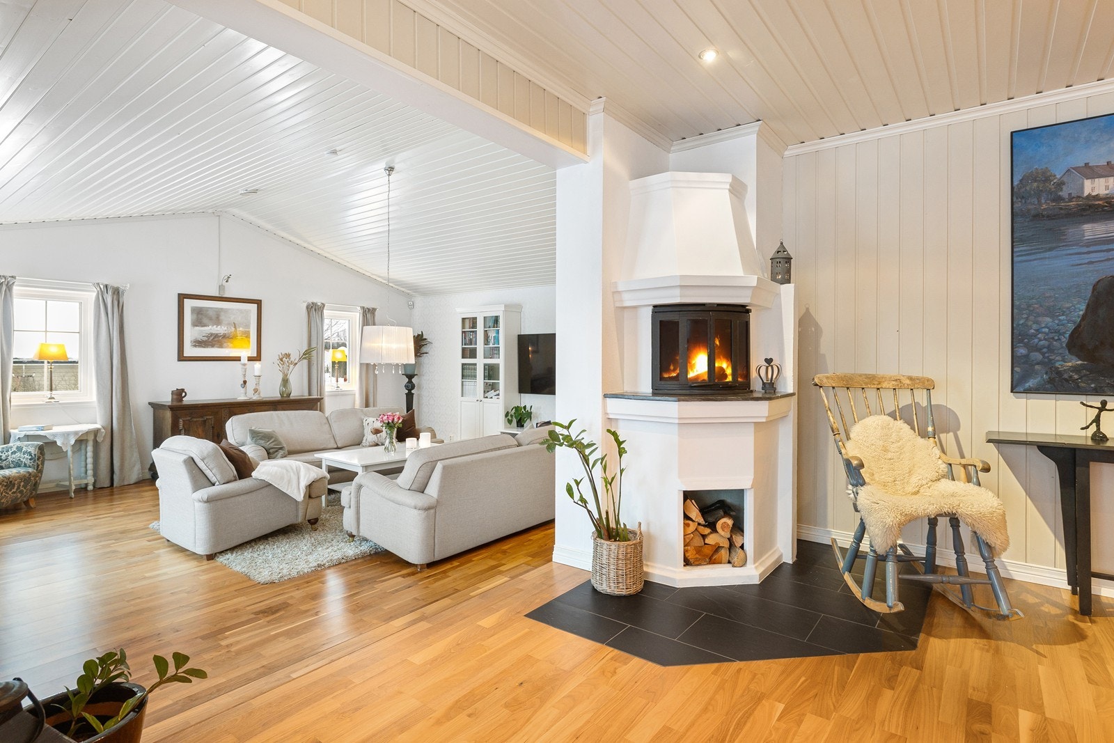 Peisen gir en innbydende velkomst inn i den lyse stuen. Galleribilde