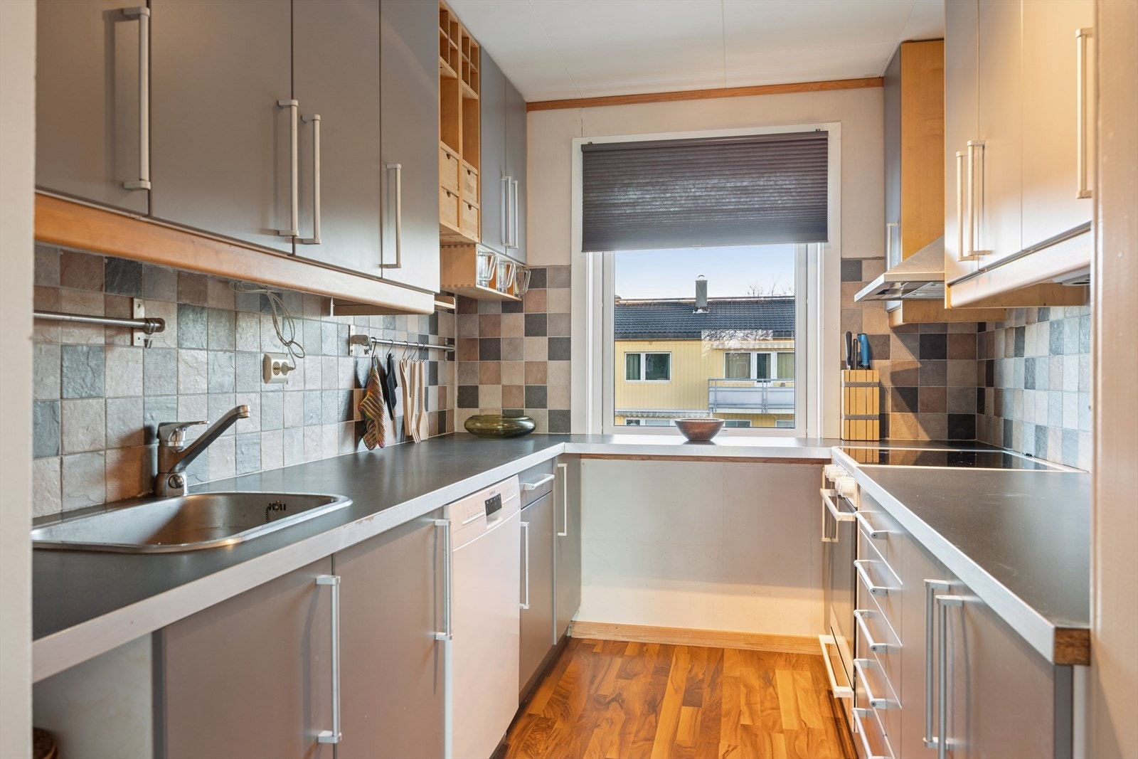 Tidløst kjøkken med flis over benk og rikelig med skap -og benkeplass. Galleribilde