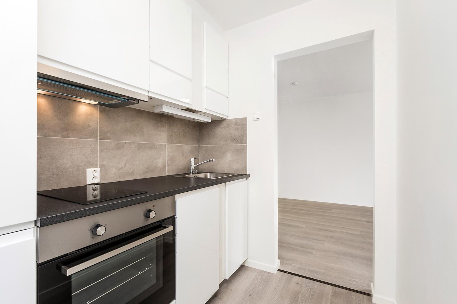 Pent kjøkken med kjøl-/fryseskap, oppvaskmaskin, stekeovn og koketopp Galleribilde