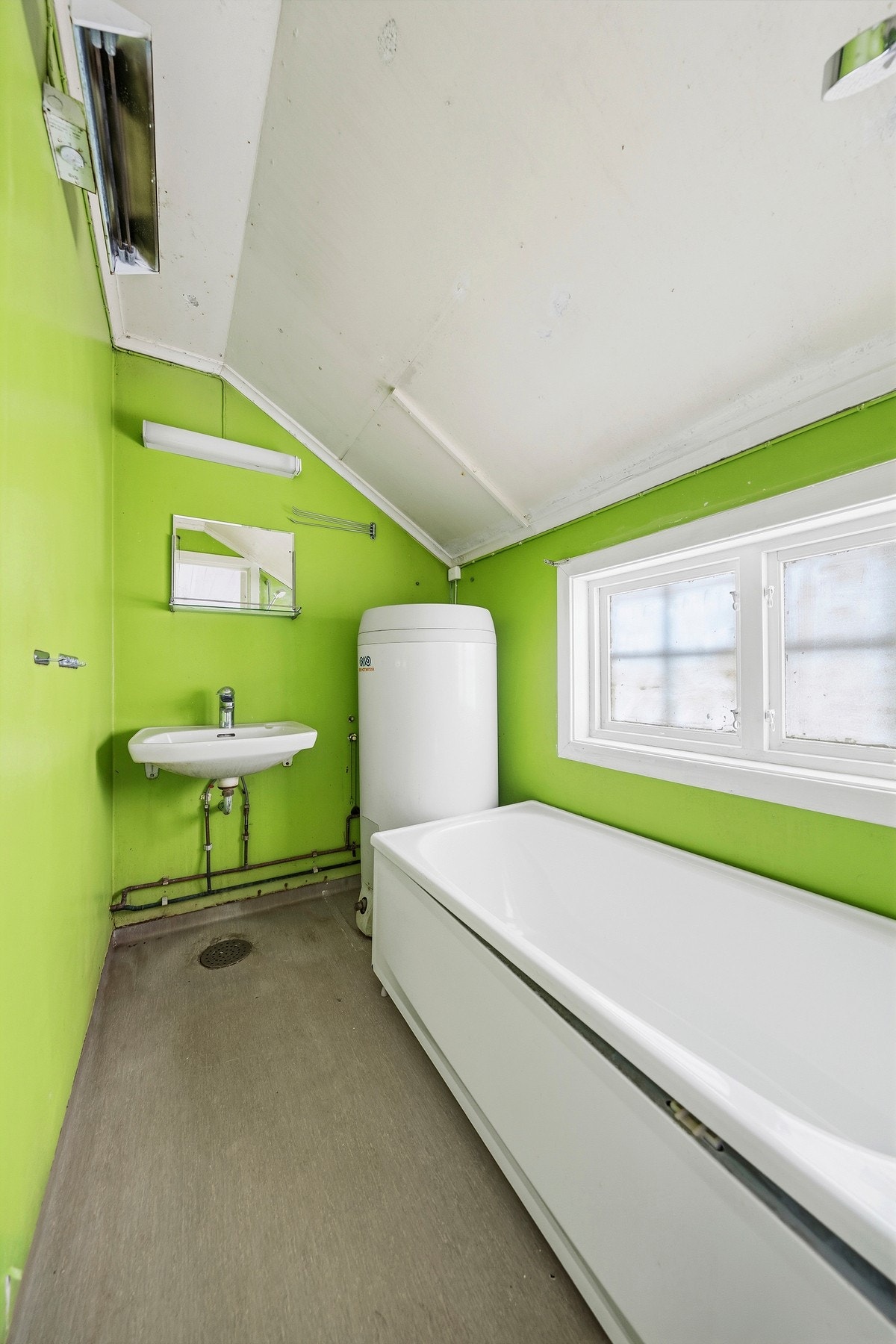 Eldre bad med badekar, servant og vindu som gir naturlig lys. Galleribilde