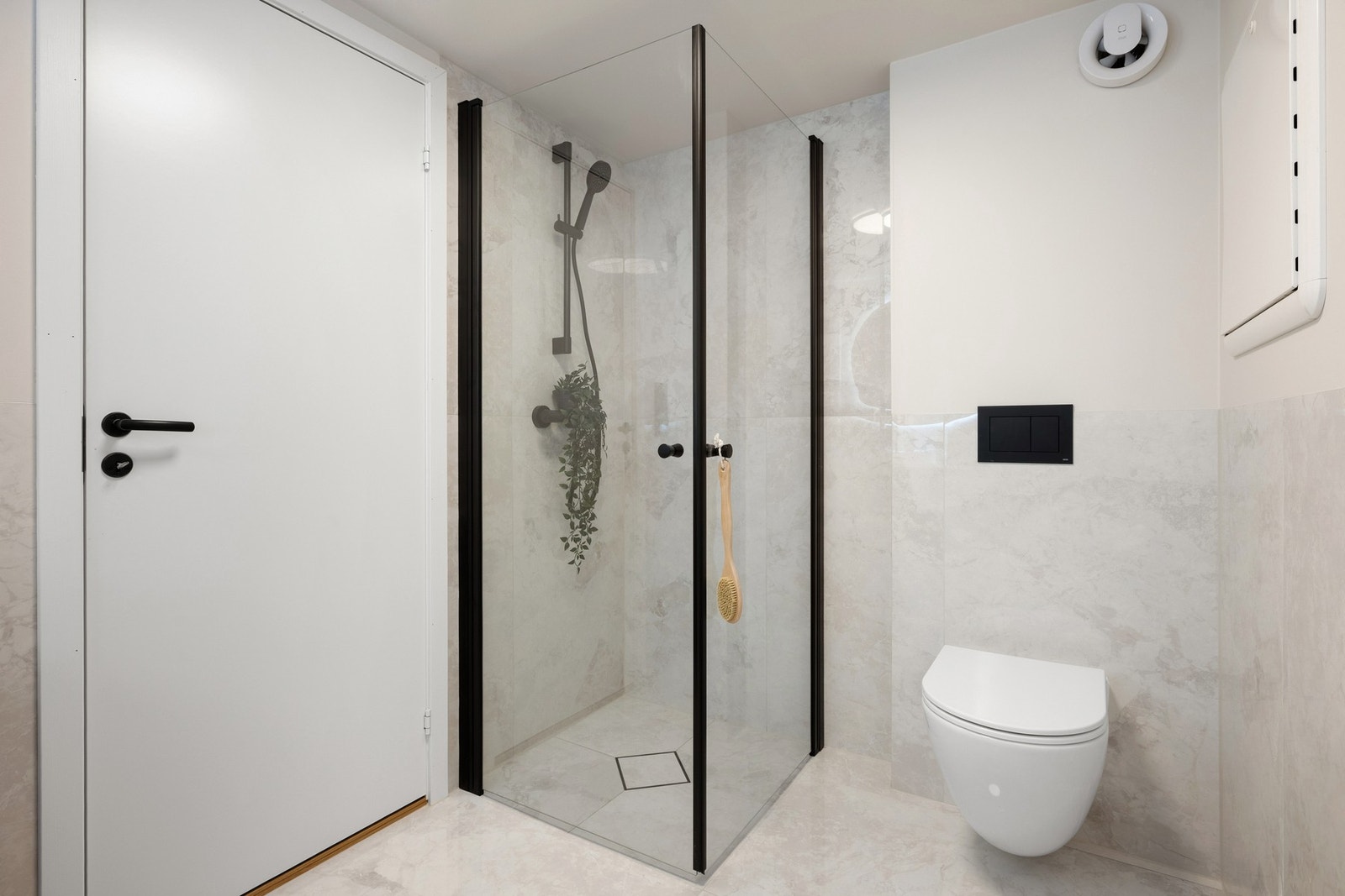 Badet er innredet med vegghengt toalett, baderomsinnredning, dusj med glassvegger og opplegg for vaskemaskin. Galleribilde