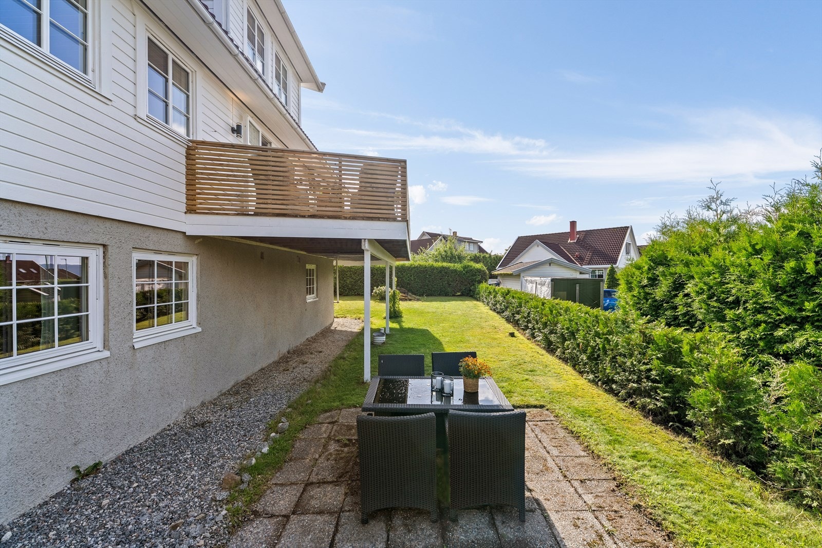 Det er en hellelagt uteplass og gruslagt stikkvei bort til inngangsdøren til sokkeletasjen. Galleribilde