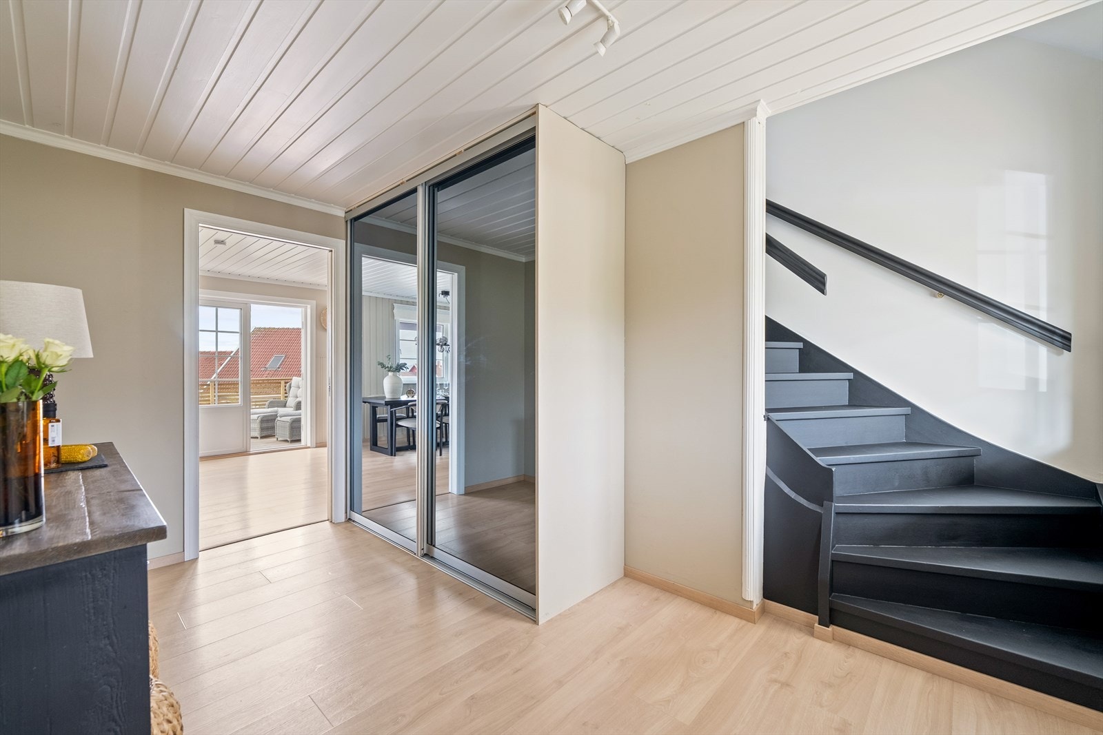 Her er det god plass til oppbevaring i en praktisk skyvedørsgarderobe med speildører, som både gir rommet et luftig uttrykk og bidrar til funksjonell lagring av yttertøy og sko. Galleribilde