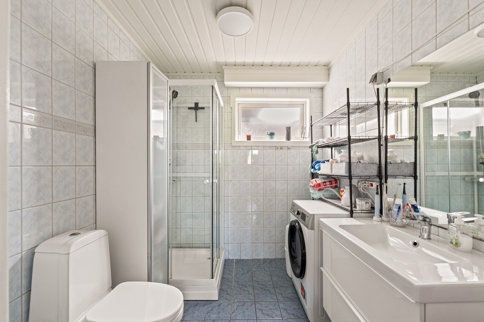 Baderommet er fra byggeåret 1999 og har flislagt gulv med behagelig gulvvarme, utstyrt med vegghengt servantskap, dusjkabinett og gulvstående toalett samt opplegg for vaskemaskin. Galleribilde