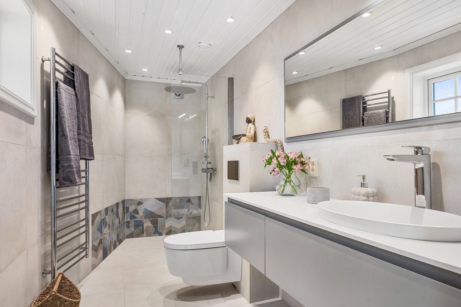 Badet i 2. etasje er fra 2019 med flislagte overflater, gulvvarme og downlights. Innerst i rommet er en dusjnisje med glassvegg, regnfallsdusj og Blücher-sluk. Galleribilde