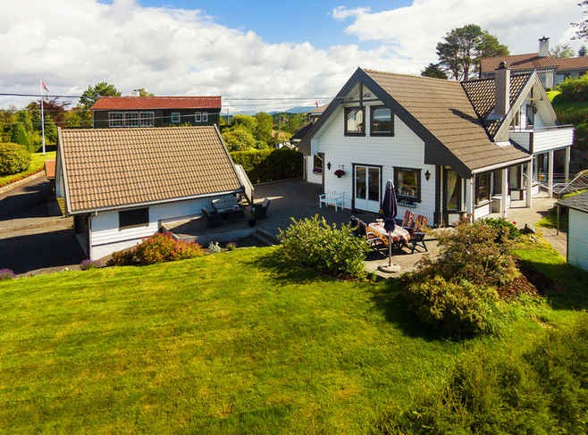 Stort fint uteområde ved inngangspartiet som er opparbeidet med plen, prydbusker og belegningsstein. Galleribilde