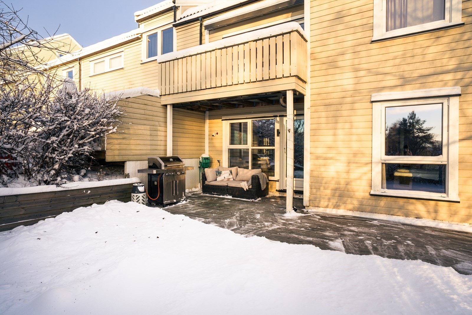 Sydvendt uteplass med terrasse og hageflekk. Deler av terrassen er overbygd. Galleribilde