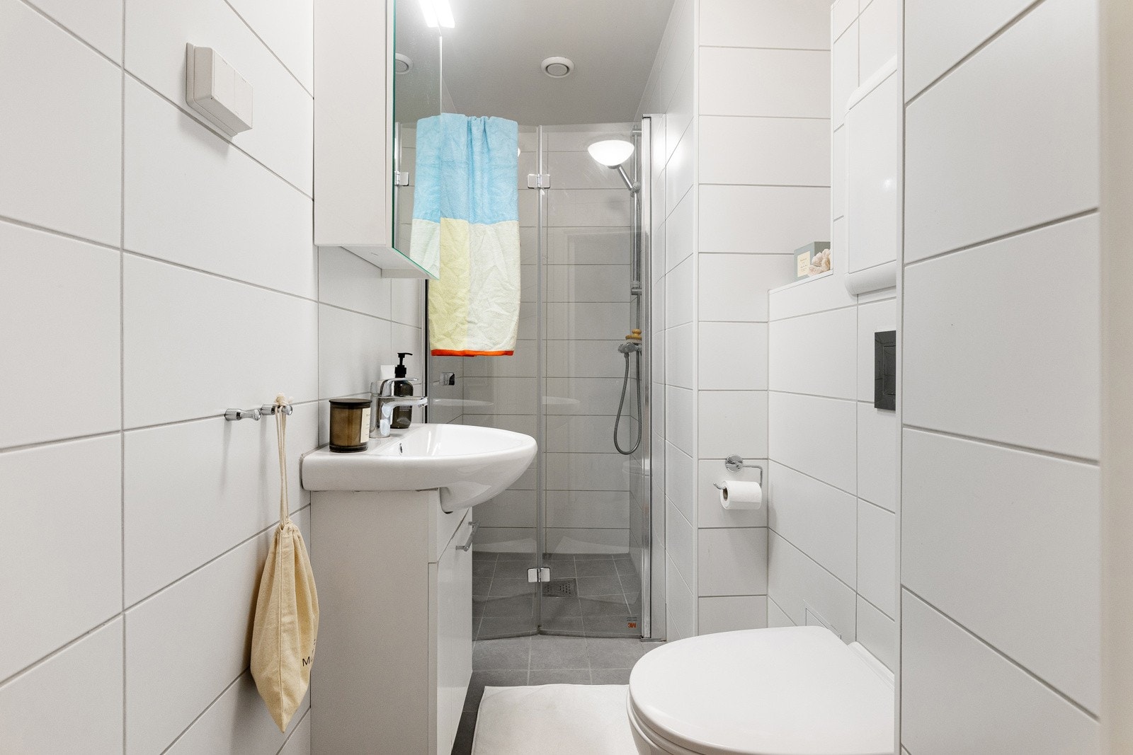 Bad med veggmontert wc og dusjhjørne med innfellbar glassdør og ettgreps krummet dusjarmatur Galleribilde