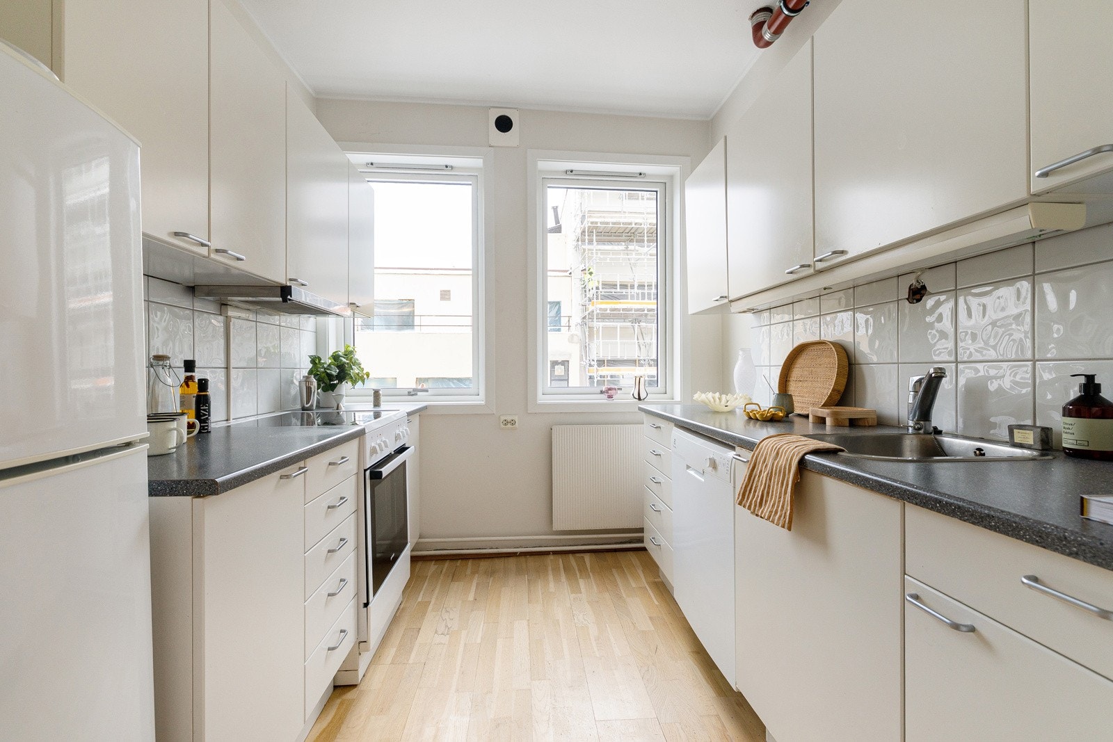 Separat kjøkken. Innredning med hvite glatte fronter og grå laminatbenkeplate med nedfelt vaskekum i børstet stål og ettgreps blandebatteri Galleribilde