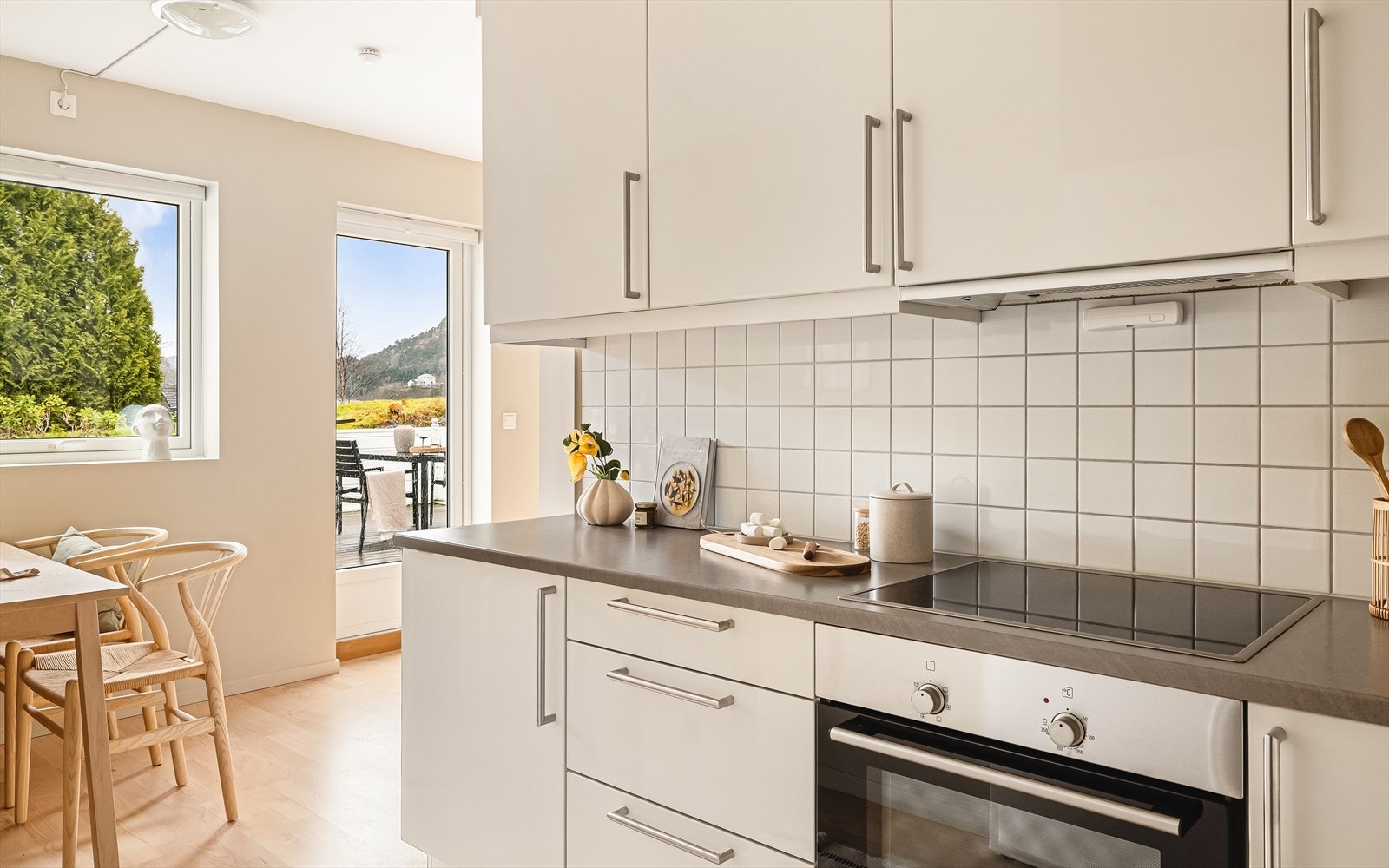 Kjøkken er stilrent og innholdsrikt. Innredning har slette hvite fronter og laminat benkeplate. Pent og praktisk med flislagt vegg mellom benkeplate og takhøye overskap. Galleribilde