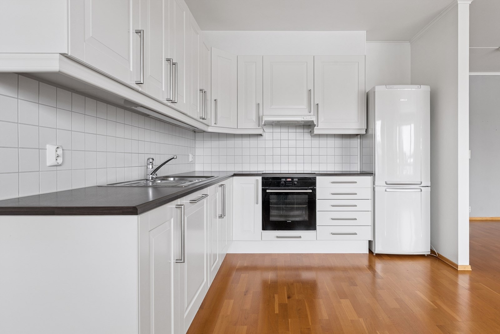 Kjøkkeninnredning med profilerte fronter, laminat benkeplate og fliser over benk. Galleribilde