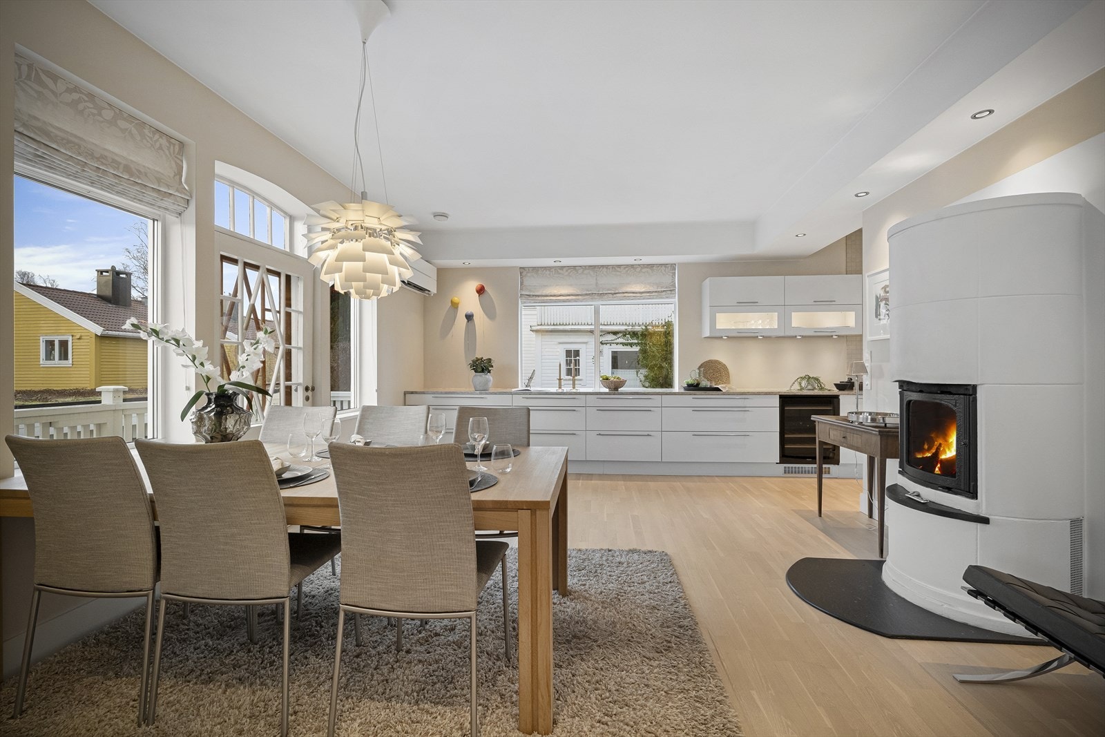 Lys og romslig spisestue med store vinduer og moderne peis Galleribilde