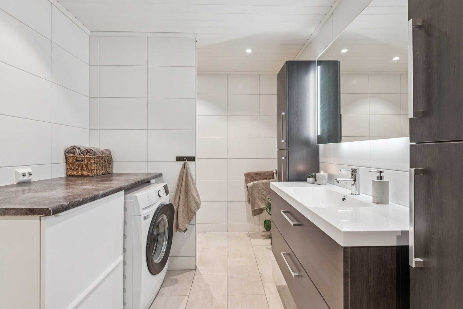 Badet har opplegg for vaskemaskin og godt med innredning til oppbevaring. Galleribilde