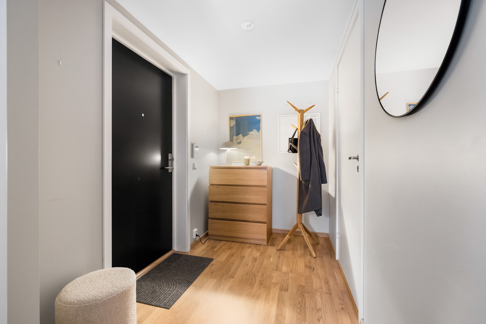 Du ønskes velkommen inn i en lysmalt gang med slette vegger og trestavs parkett på gulvene. Her har du god plass en til plassbygget garderobeløsning eller kommode for oppbevaring av yttertøy. Galleribilde