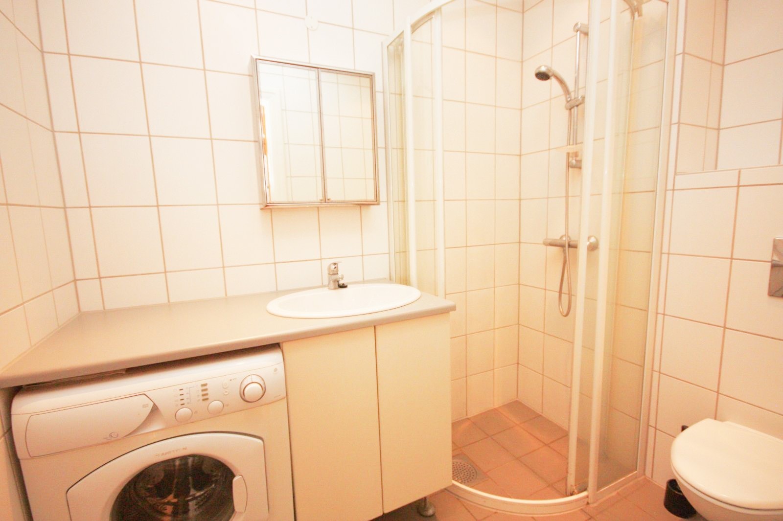 Baderom med servant, dusjhjørne, wc og vaskemaskin Galleribilde