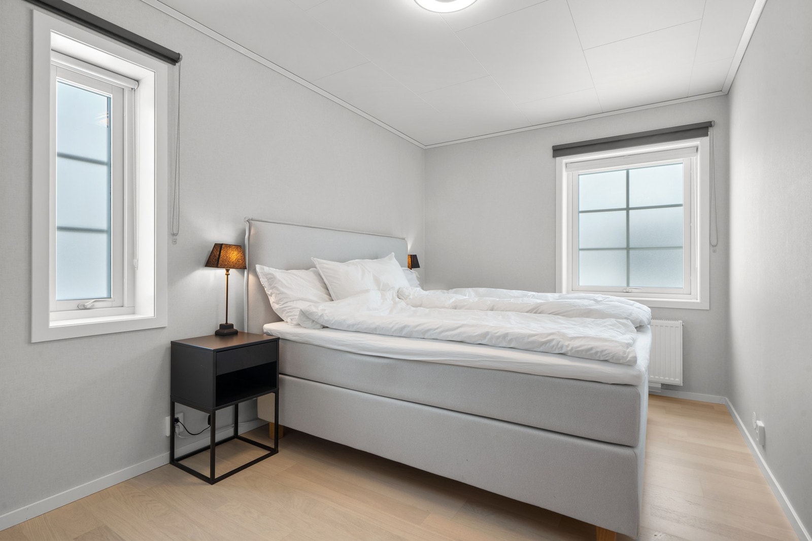 Lyst og pent hovedsoverom med vinduer mot to ulike himmelretninger som gir et fint lysinnslipp. Soverommet har lys laminat på gulv, lyse veggoverflater og skjult elektrisk anlegg. Galleribilde