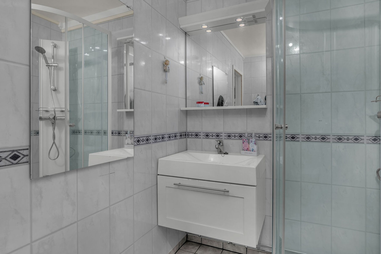 Helfliset bad med servant på innredning, speil med integrert lys, dusjkabinett og toalett. Galleribilde