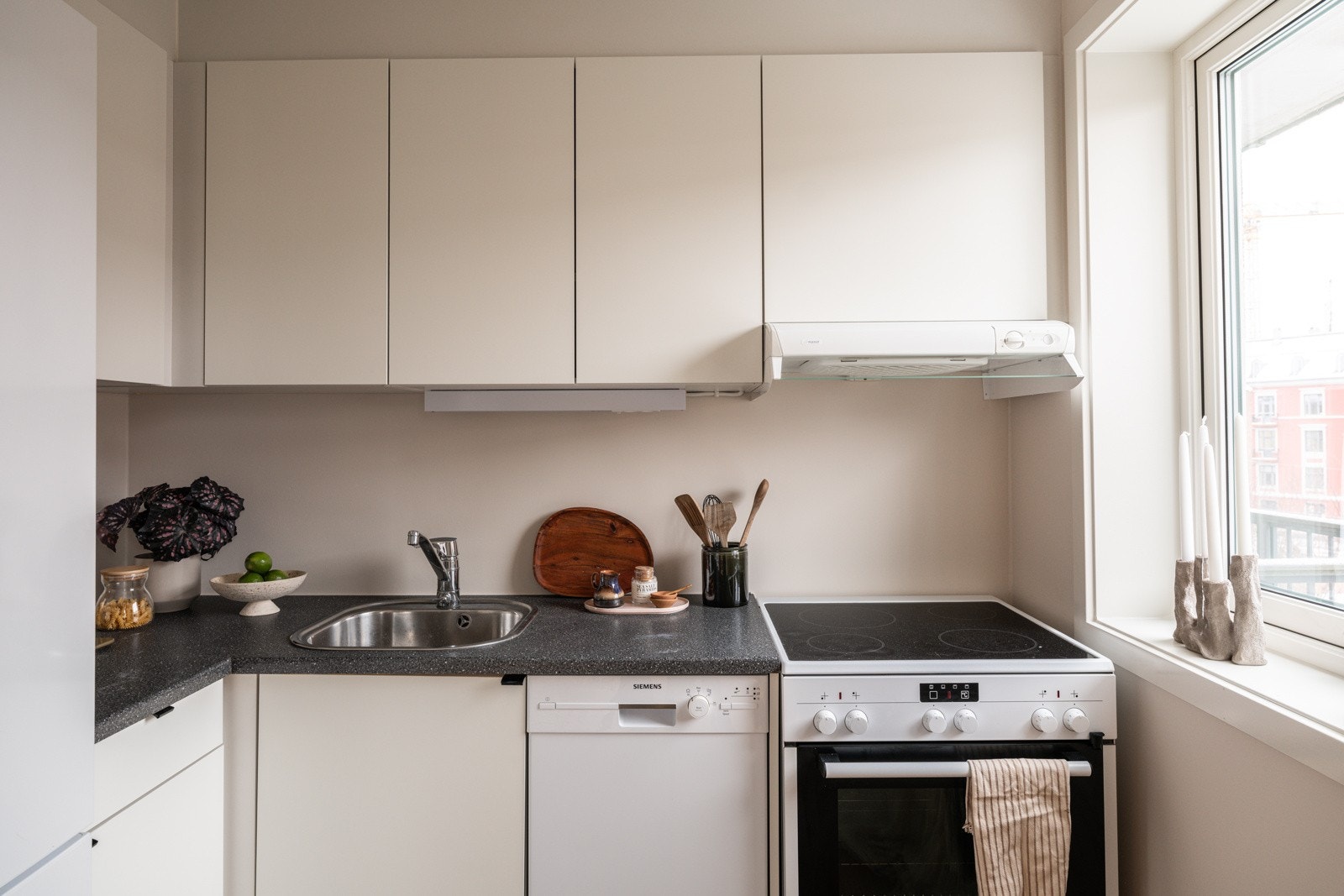 Lys og tidløs kjøkkeninnredning fra 2015 med hvite glatte fronter og laminert benkeplate med nedfelt oppvaskkum. Praktisk med belysning under overskapene. Galleribilde