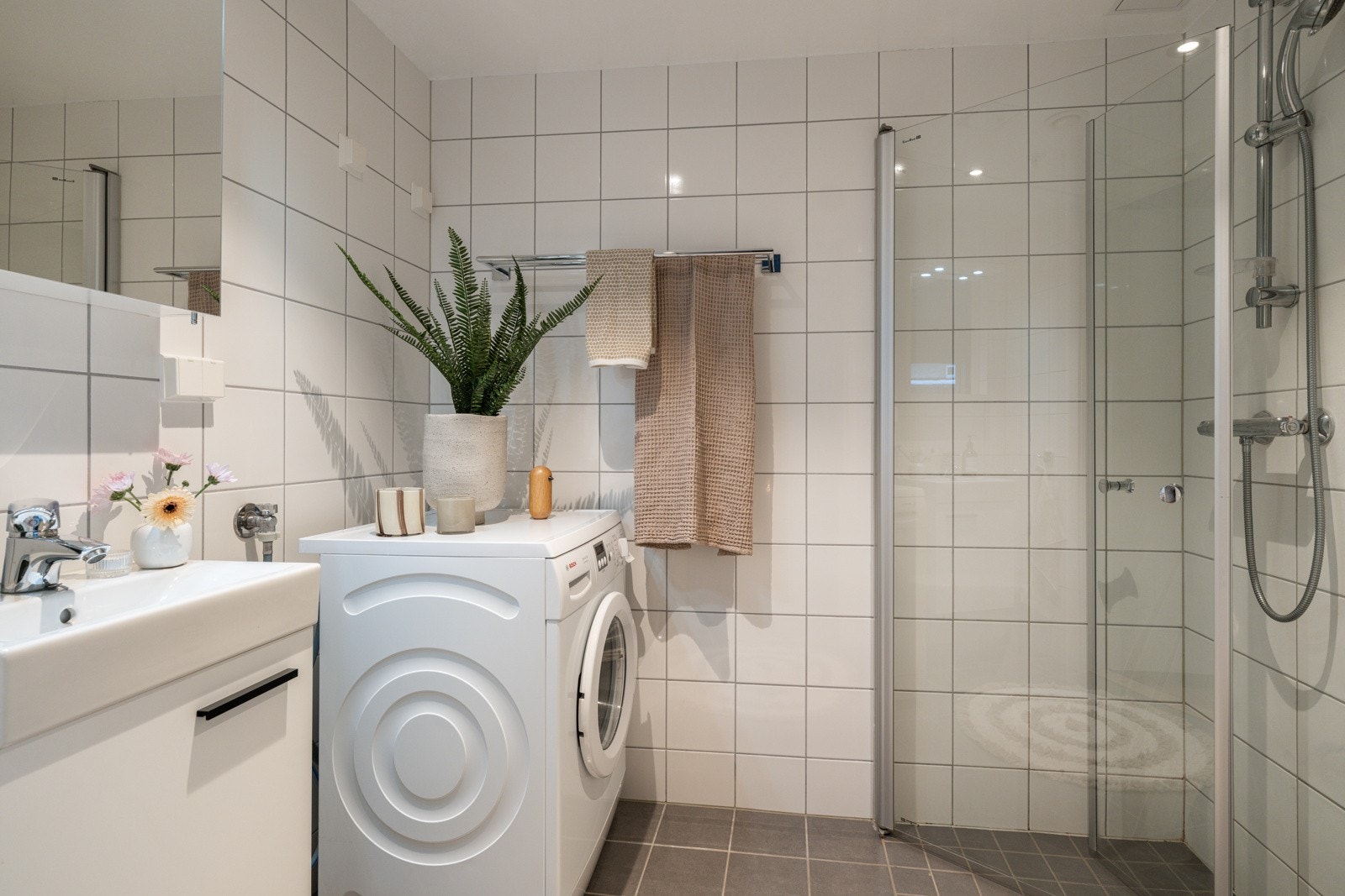 Leiligheten har et lyst og moderne baderom fra 2015. I hjørnet er det plass og opplegg for vaskemaskin. Vaskemaskinen medfølger i handelen. Galleribilde