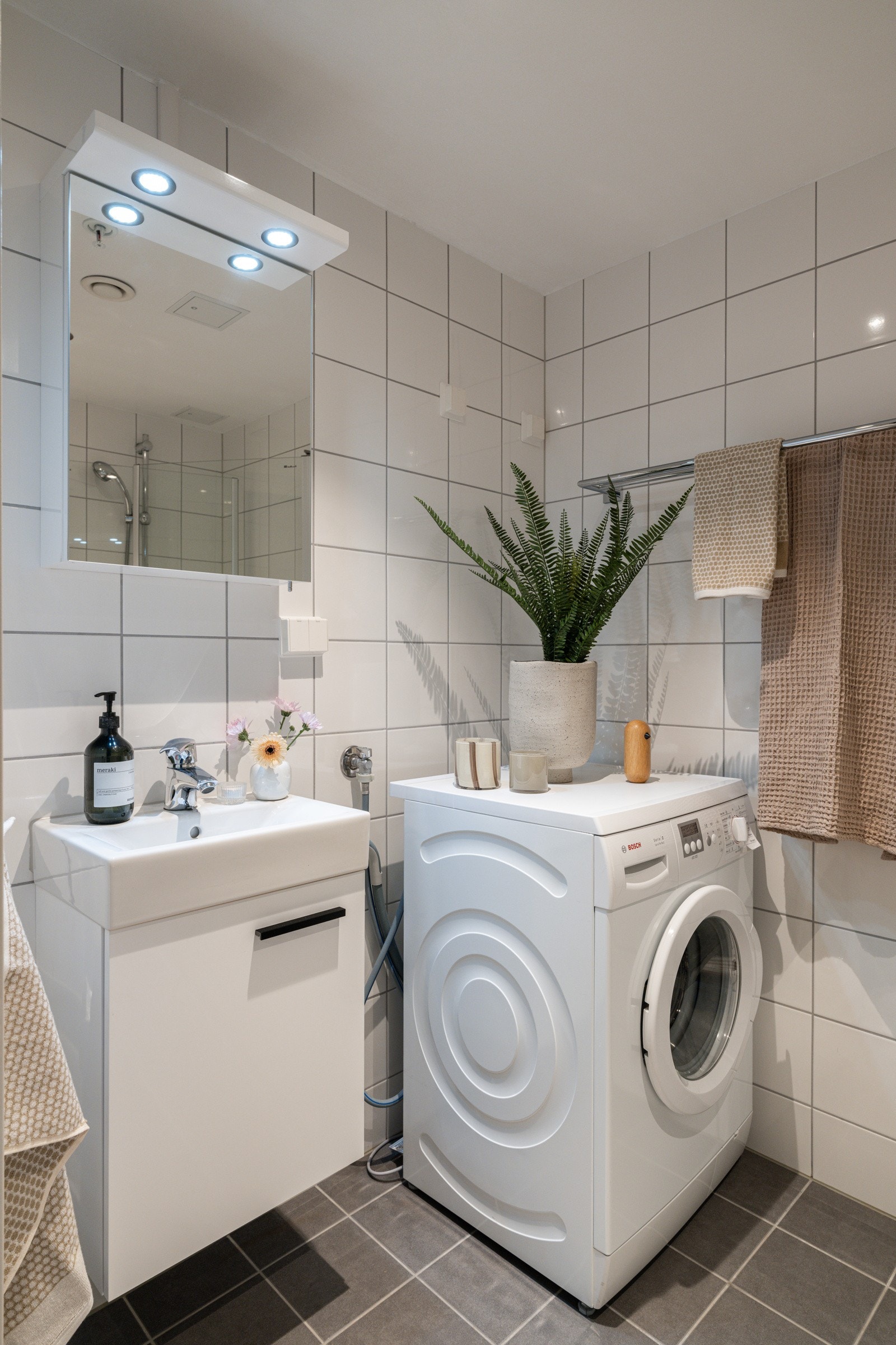 Baderommet er utstyrt med lyst servantskap med speilskap og belysning over, dusjhjørne med innfellbare glassdører og vegghengt toalett. Galleribilde