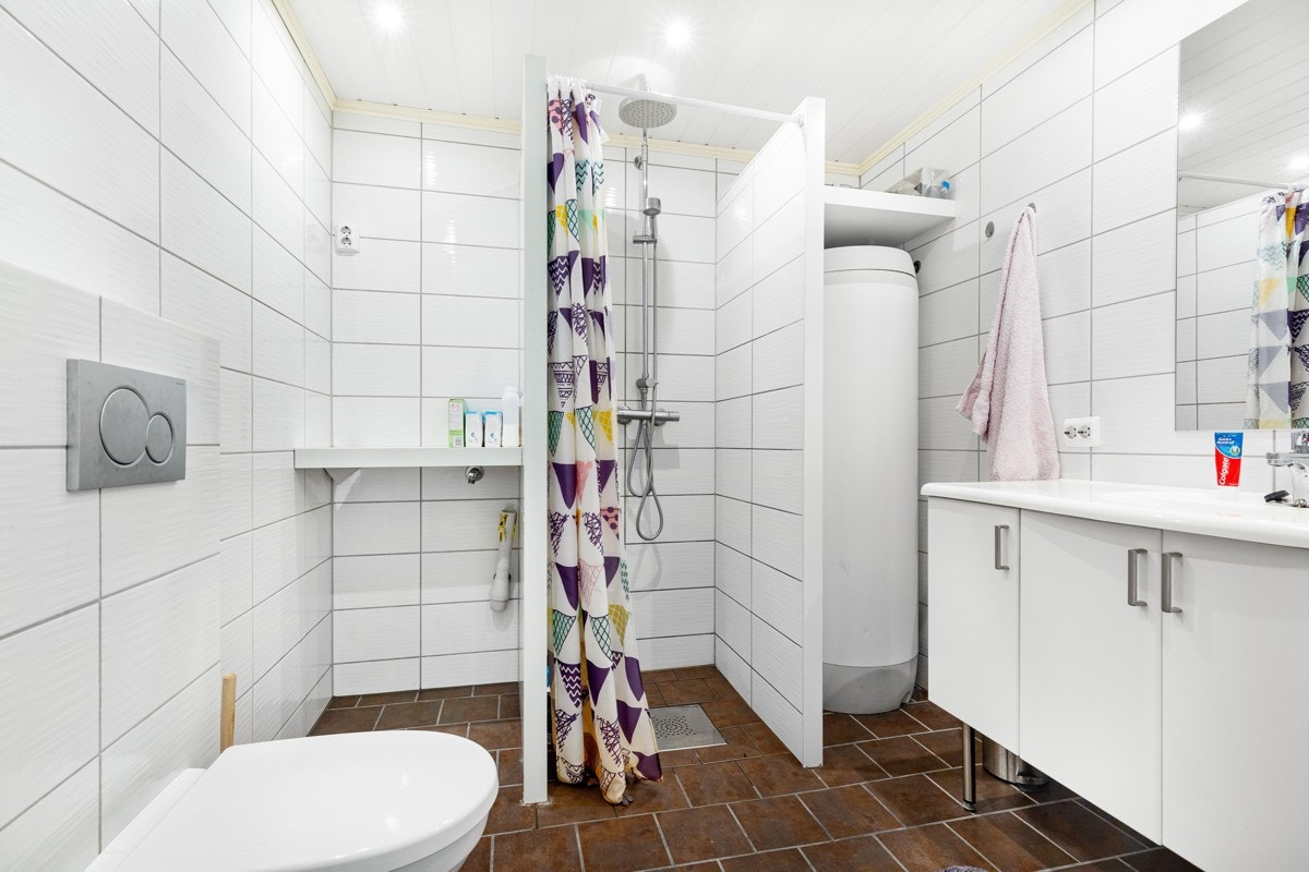 Baderom med flisbelagte vegger og gulv.