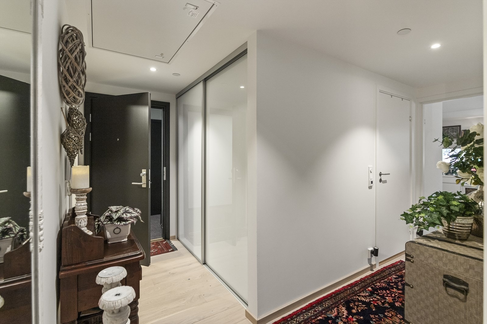 Førsteinntrykket i leiligheten er en romslig entré der yttertøyet enkelt kan henges i en integrert skyvedørsgarderobe. Galleribilde