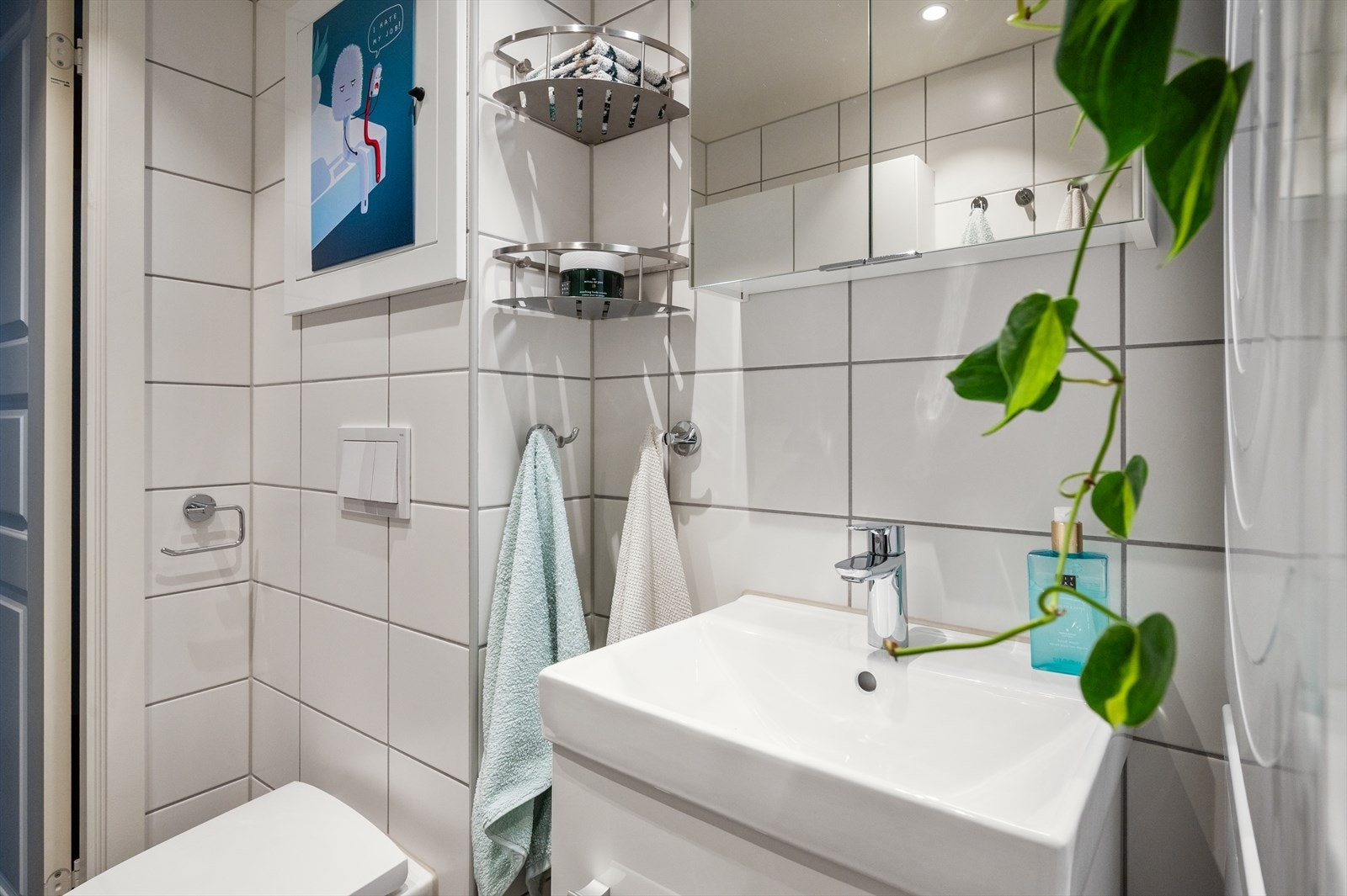 Servantskap med slette fronter samt speilskap på vegg over servant. Det er opplegg for vaskemaskin, veggmontert toalett og dusjhjørne med buede svingdører. Det er varmekabel i gulv. Galleribilde