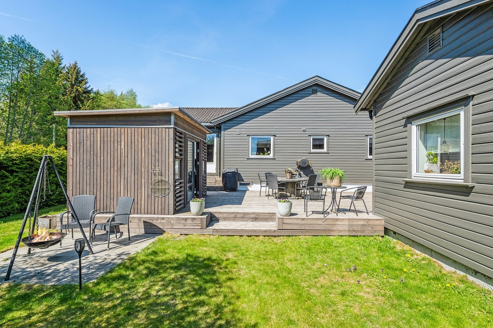 Tomten er pent opparbeidet med gressplen, beplantninger og prydbukser. Galleribilde