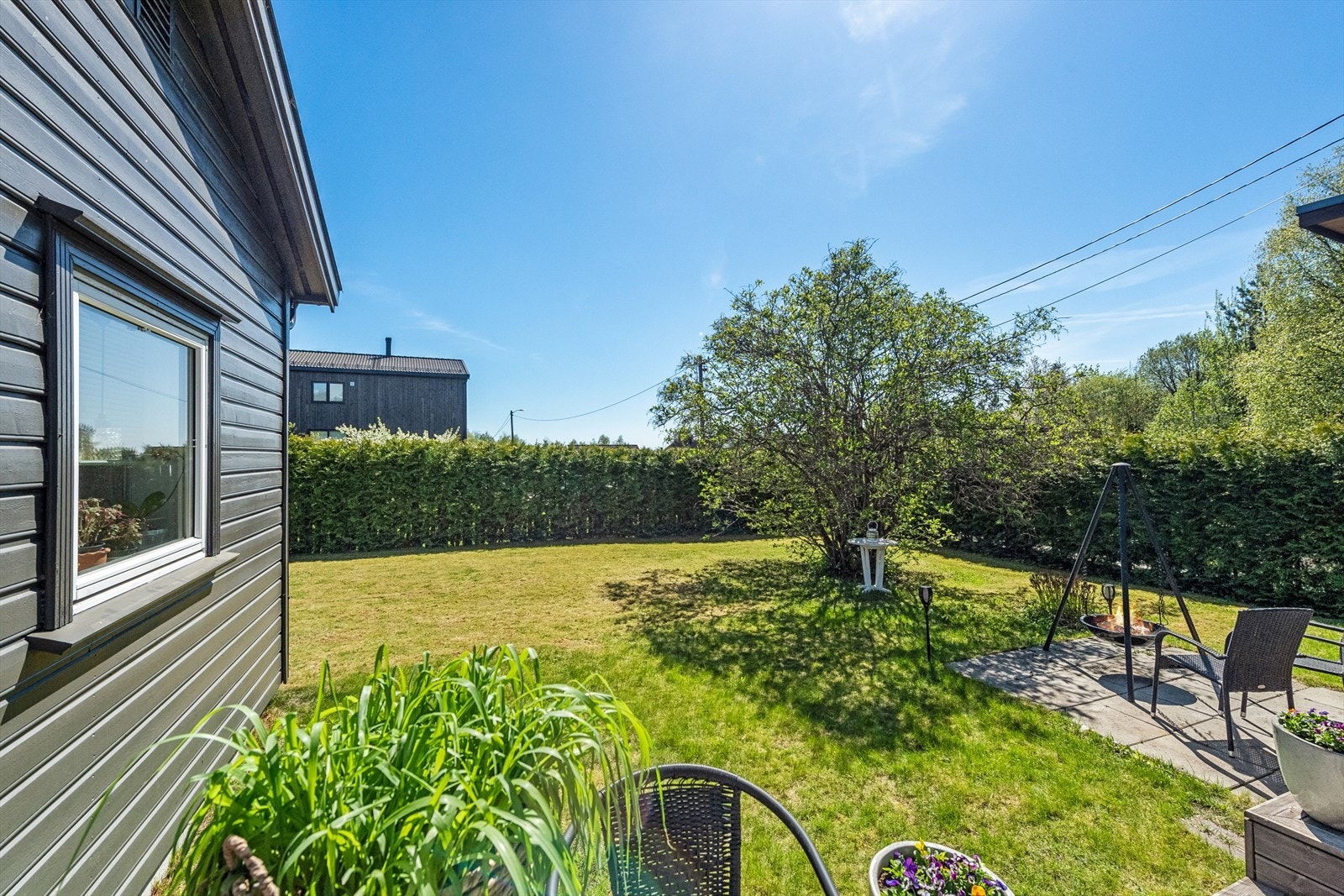 Tomten er pent opparbeidet med gressplen, beplantninger og prydbukser. Galleribilde