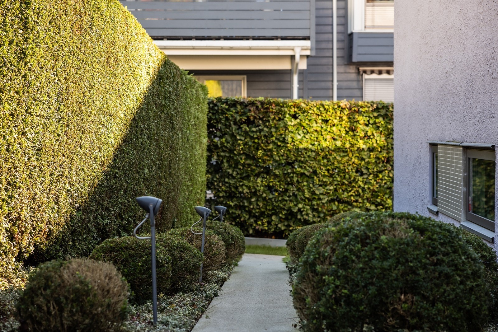 Stilig og påkostet tomt/uteplasser med platting og gangvei i lys pigmentert betong, skiferheller, gatestein, utvendig belysning mm. Galleribilde