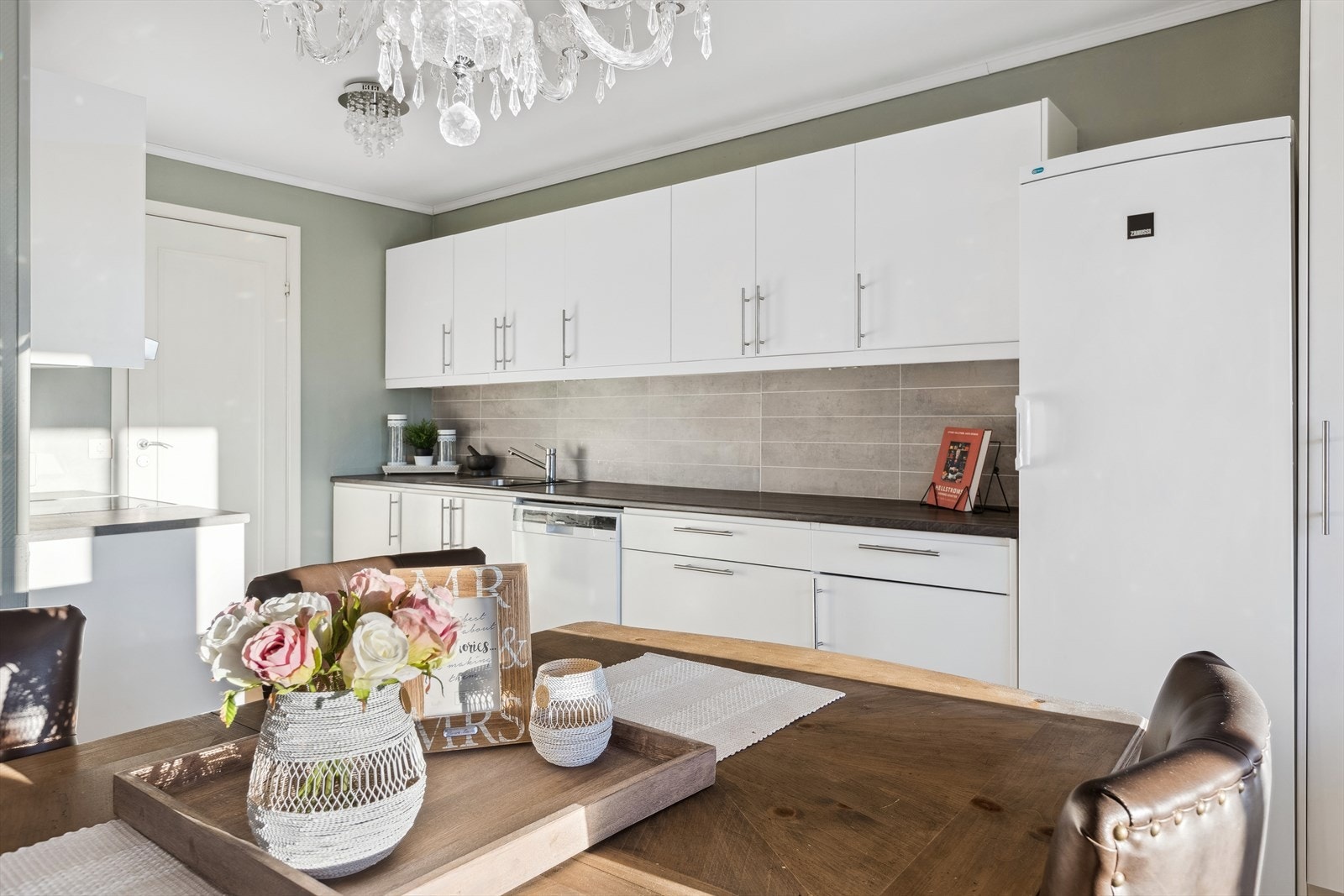 Kjøkkeninnredningen har hvite, slette fronter og laminat benkeplate. Galleribilde