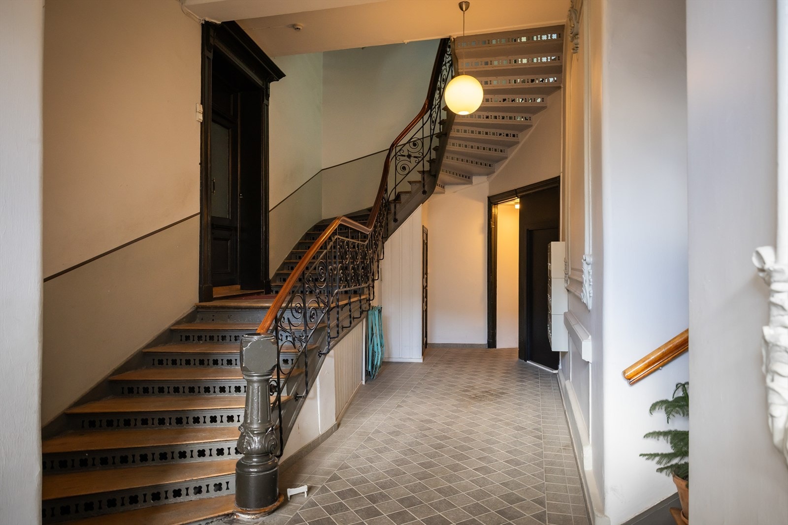 Oppgang med flislagt gulv og smiejernsrekkverk opp langs trappeløpet Galleribilde