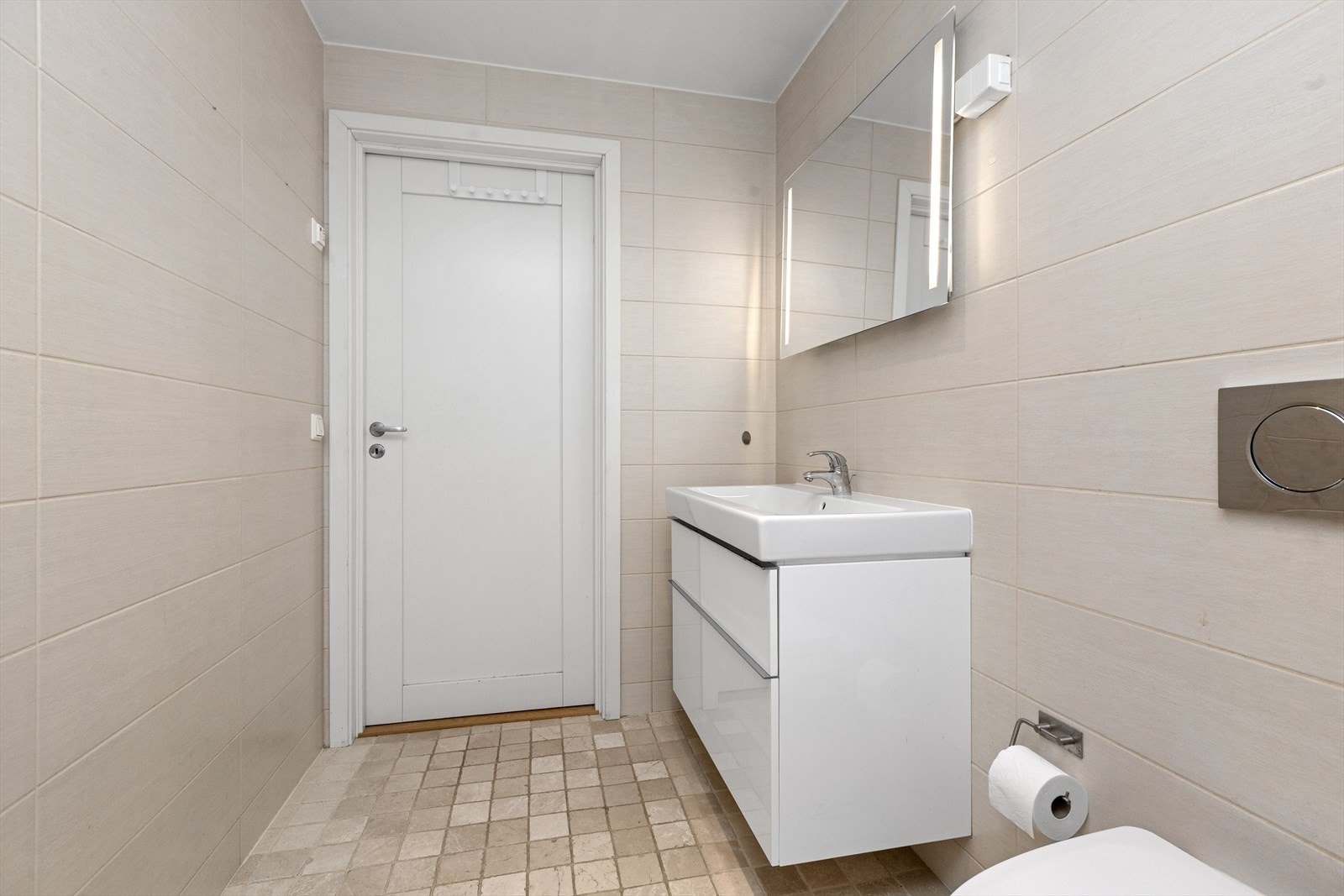 Baderommet er innredet med vegghengt klosett, hvit innredning med nedfelt servant og dusjhjørne med svingbare dører. Galleribilde