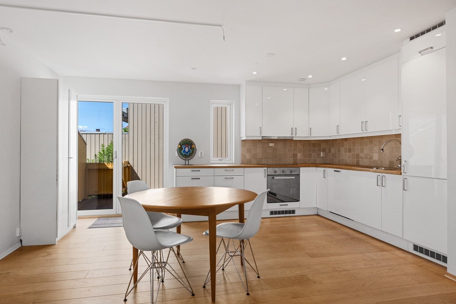 Kjøkkenet har en moderne innredning med glatte, hvite fronter i høyglans og en benkeplate med nedfelt vaskekum. Galleribilde