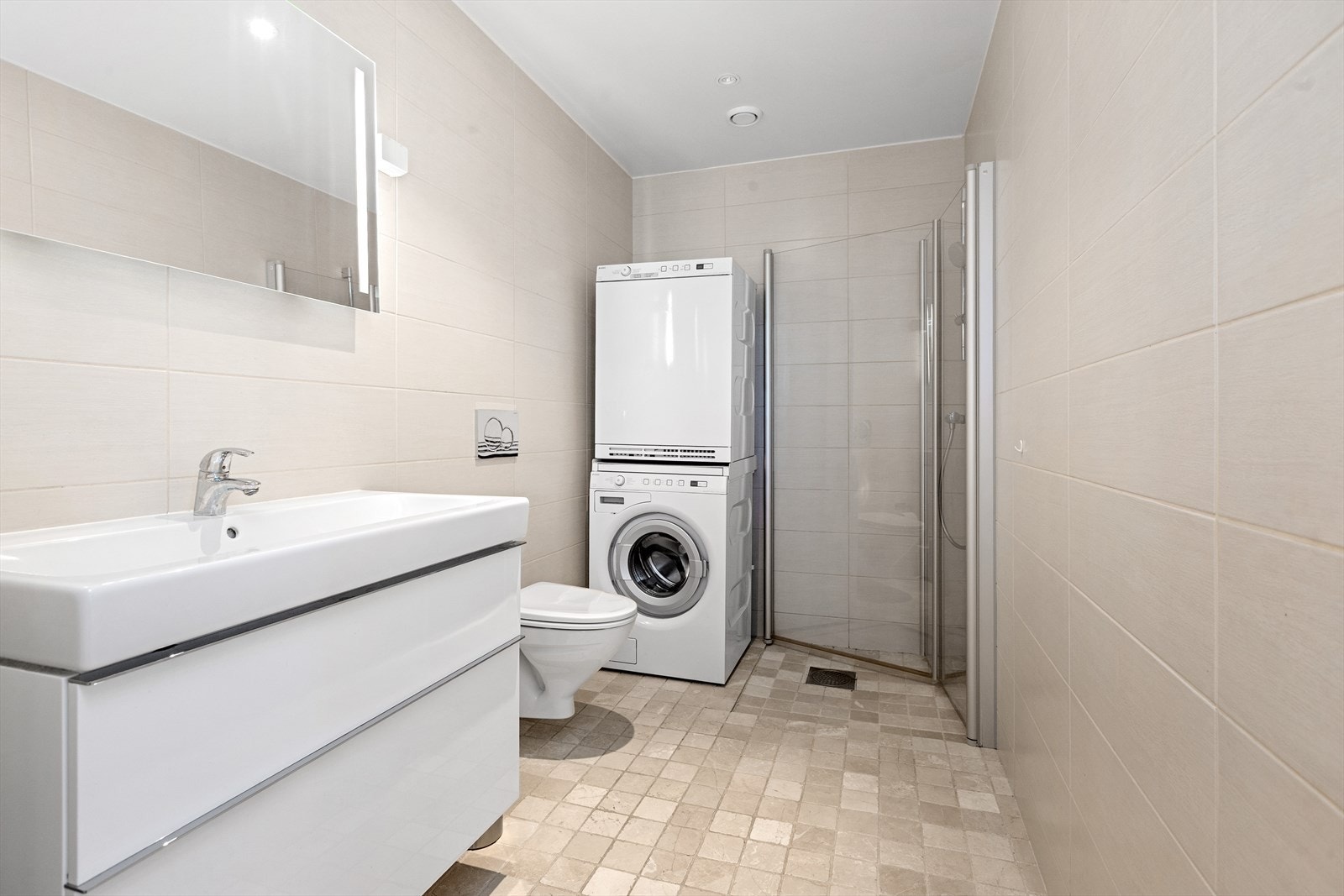 Baderommet er flislagt i lyse farger og har opplegg for vaskemaskin. Galleribilde