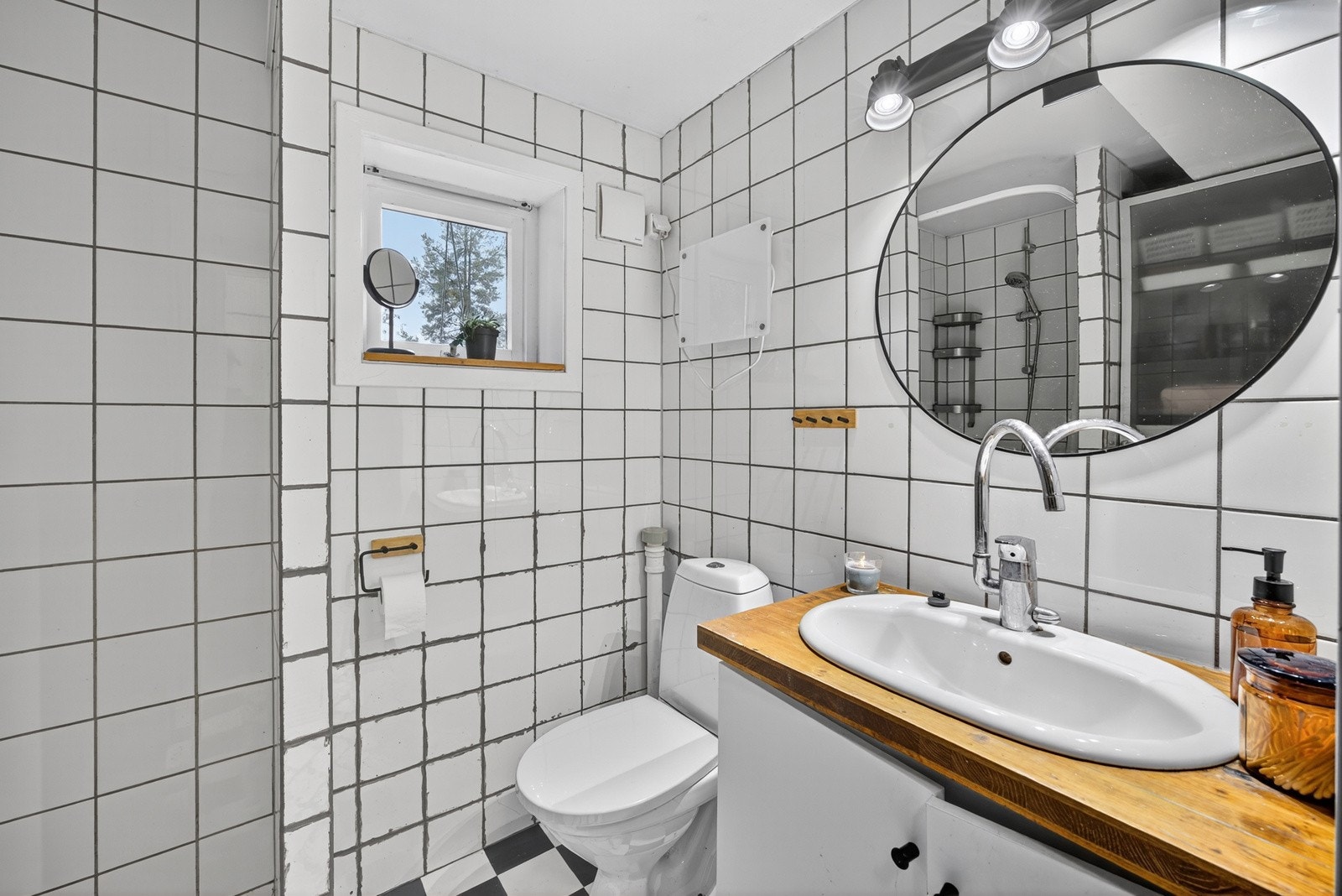 Eldre bad fra byggeår, med fliser på vegg og vinylbelegg på gulv. Baderomsinnredningen består av vegghengt servantmøblement, samt speil med lys over servant. Galleribilde