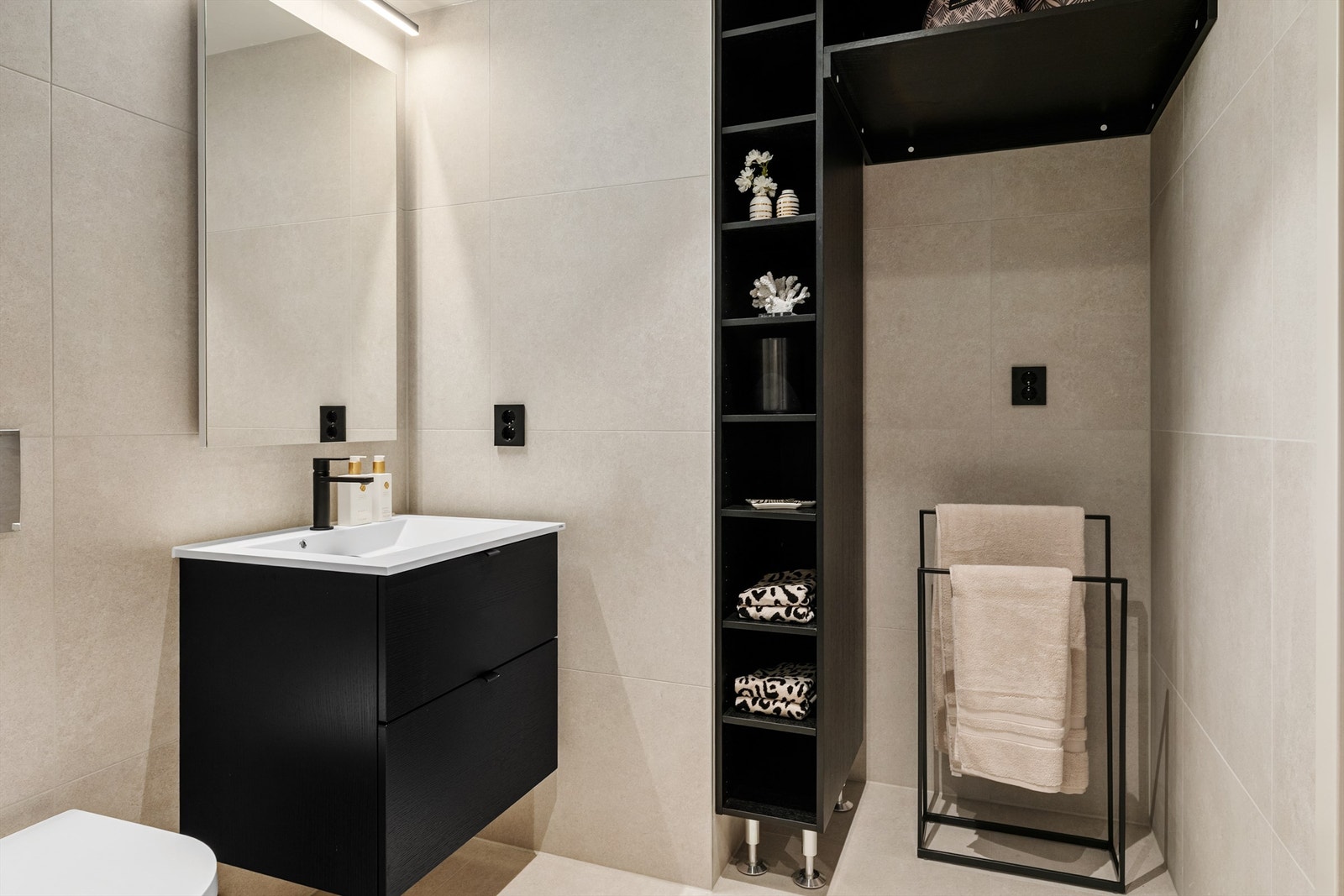 Pent flislagt baderom med praktisk hylleløsning og opplegg for vaskemaskin. Galleribilde