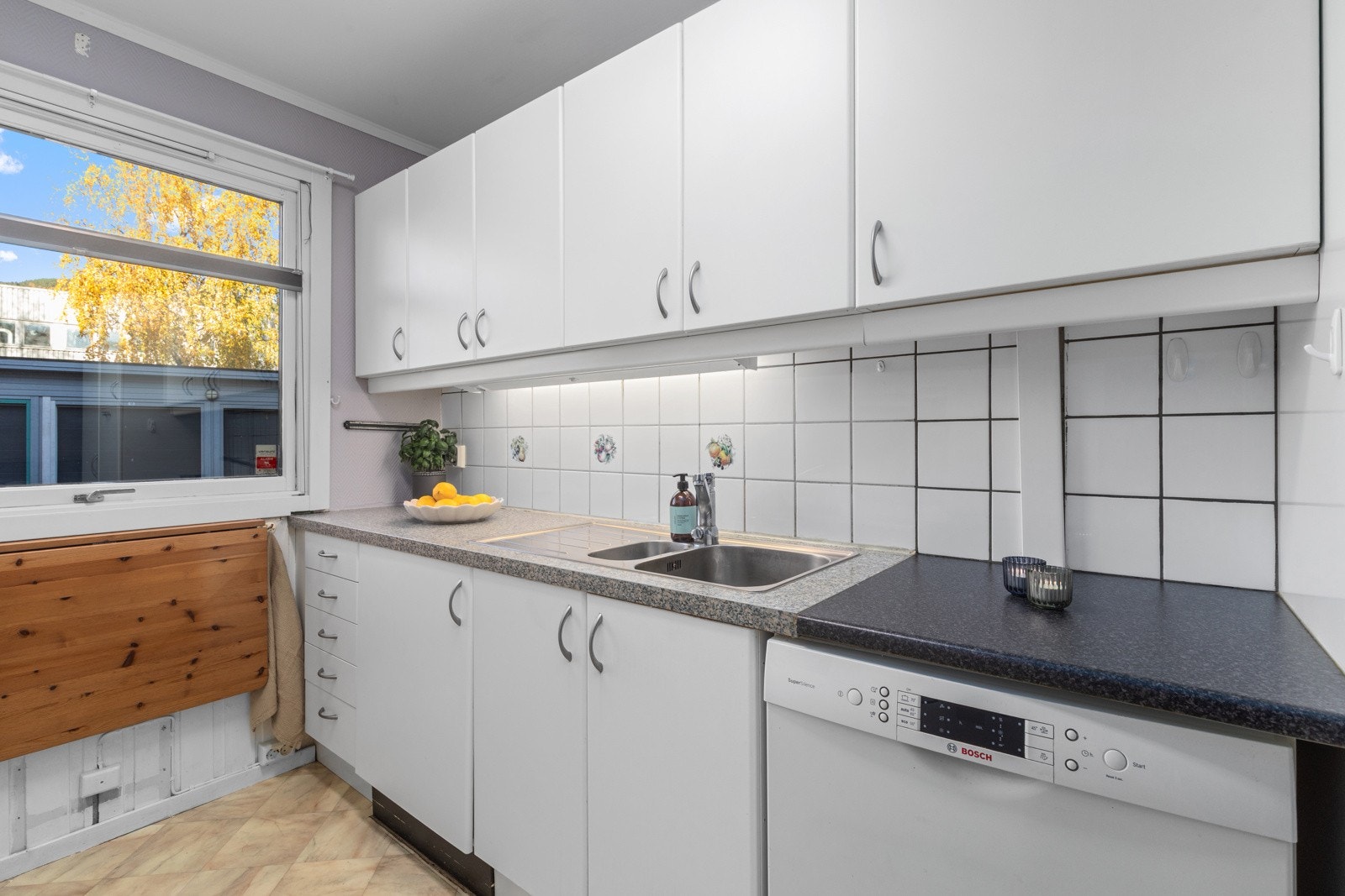 Lyst separat kjøkken med hvite slette fronter, benkeplate av laminat og nedfelt oppvaskkum. Galleribilde