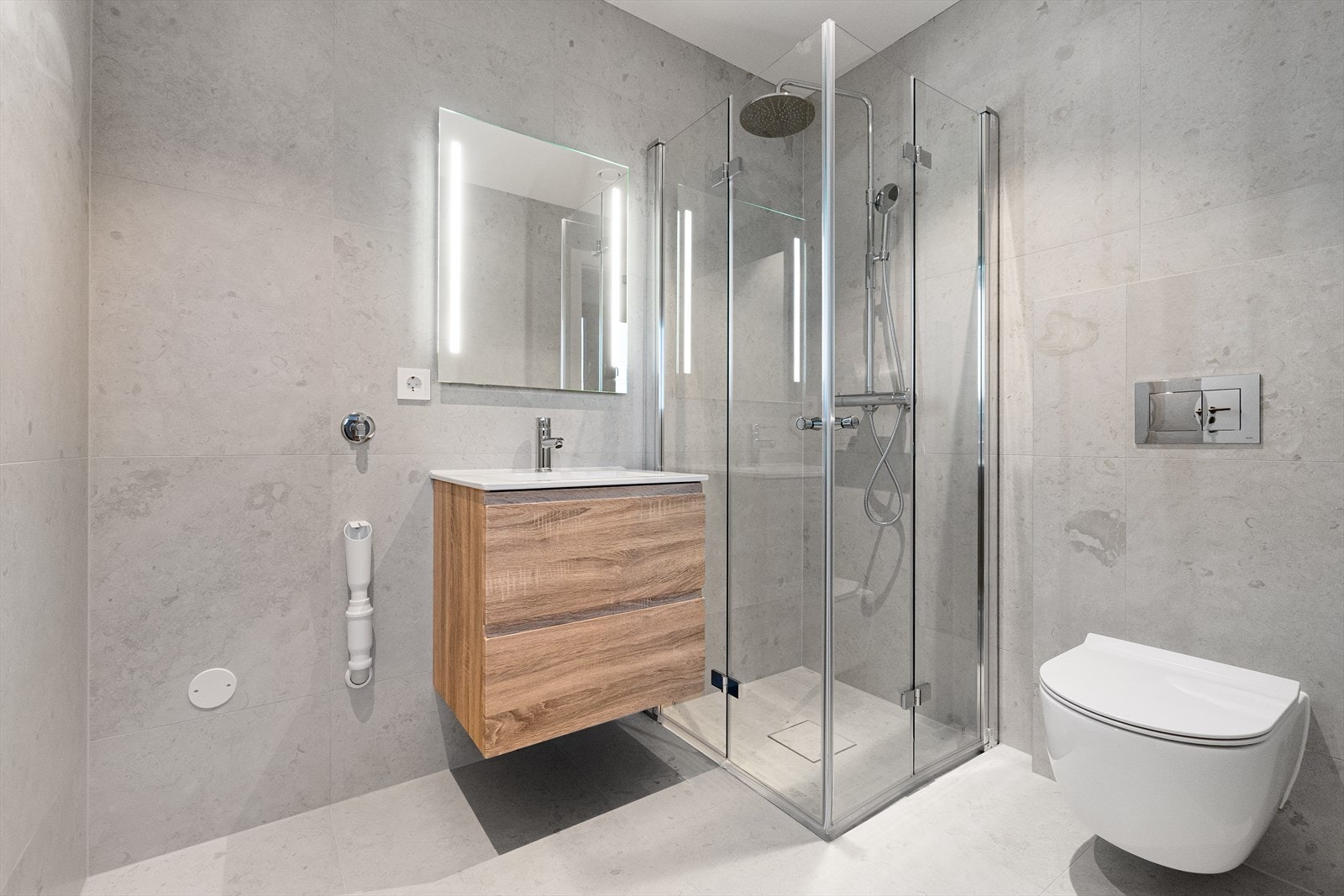 Flott og moderne bad, innredet med servant i innredning med skuffer, speil med belysning, dusj og toalett. Opplegg til vaskemaskin Galleribilde