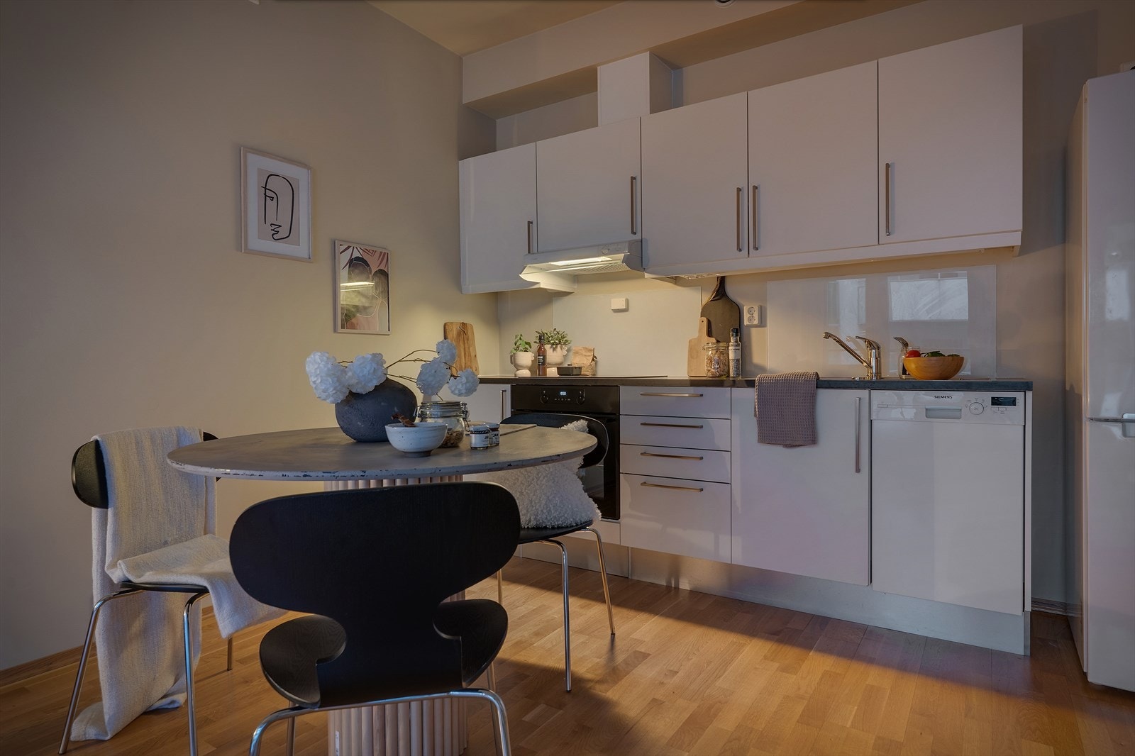 Kjøkkenet har innredning med hvite slette laminerte fronter og sort laminert benkeplate Galleribilde