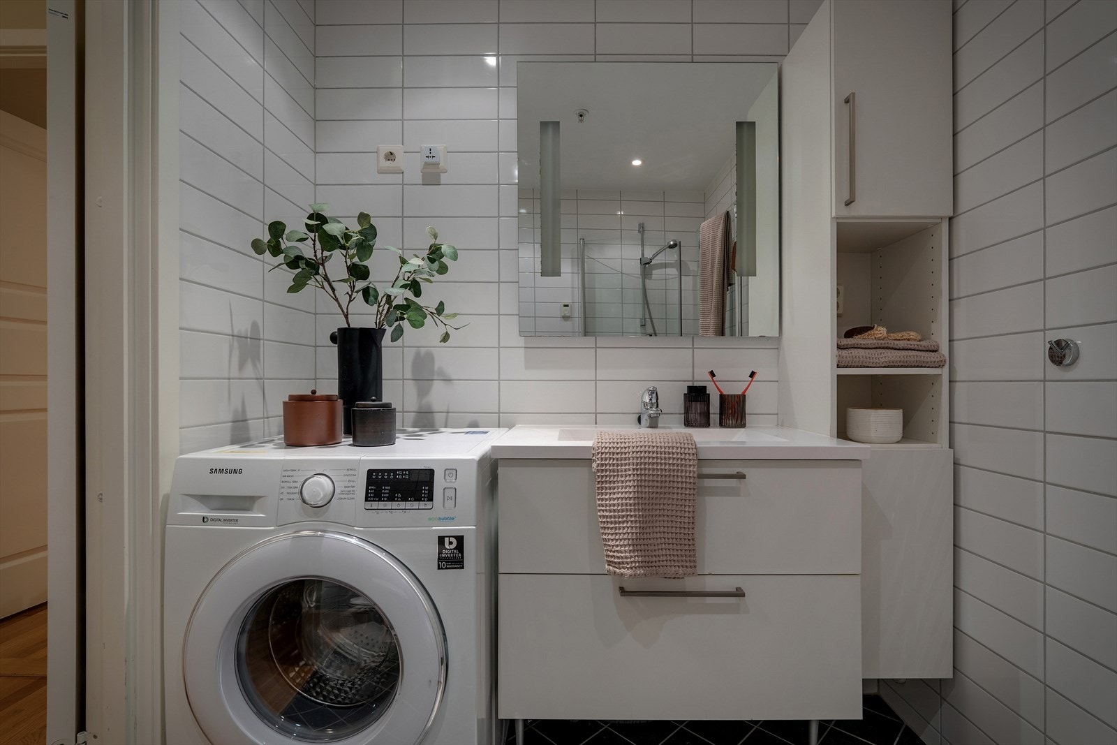 Her er det utstyrt med innfellbart dusjhjørne av glass, vegghengt klosett, baderomsinnredning med servant og belyst speil. Badet har også opplegg for vaskemaskin Galleribilde