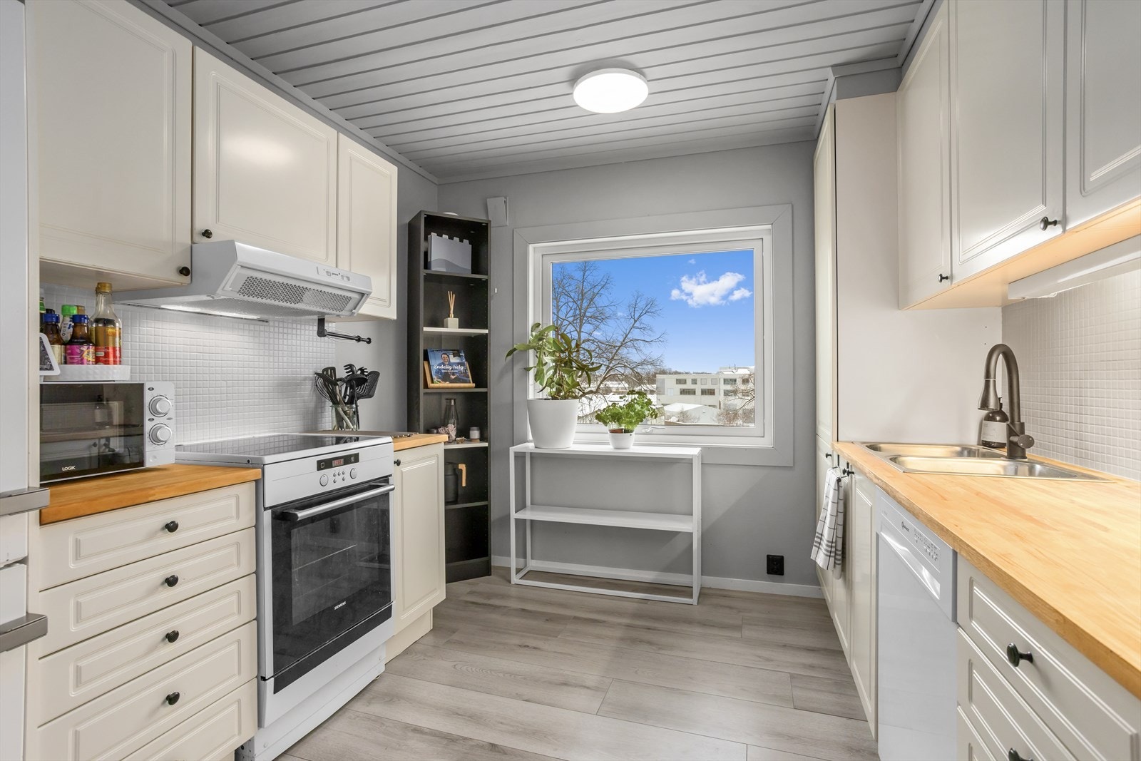 På kjøkkenet er det god benkeplass og rikelig med oppbevaringsplass. Kjøkkenet er innredet med en klassisk, lys og profilert kjøkkeninnredning, praktisk tilpasset rommets utforming. Galleribilde